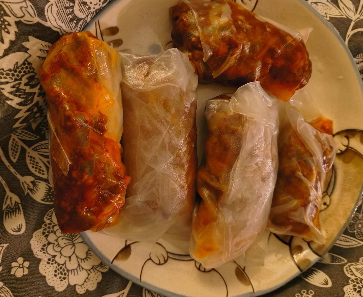 Sepiring lumpia dibungkus kertas nasi, diisi sayuran, daging, dan saus
