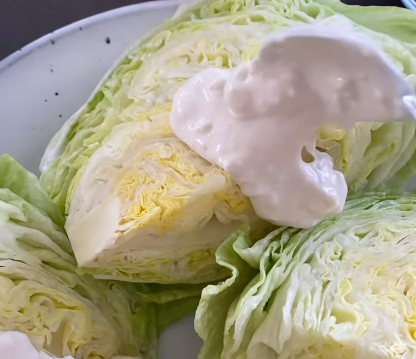 Wedge of iceberg lettuce topped with a dollop of creamy dressing connected  a plate