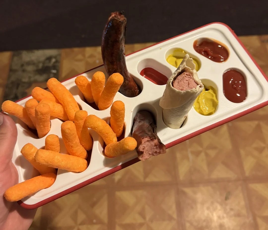 Makanan ringan disusun dalam nampan es batu berisi keju, sosis, saus tomat, dan mustard