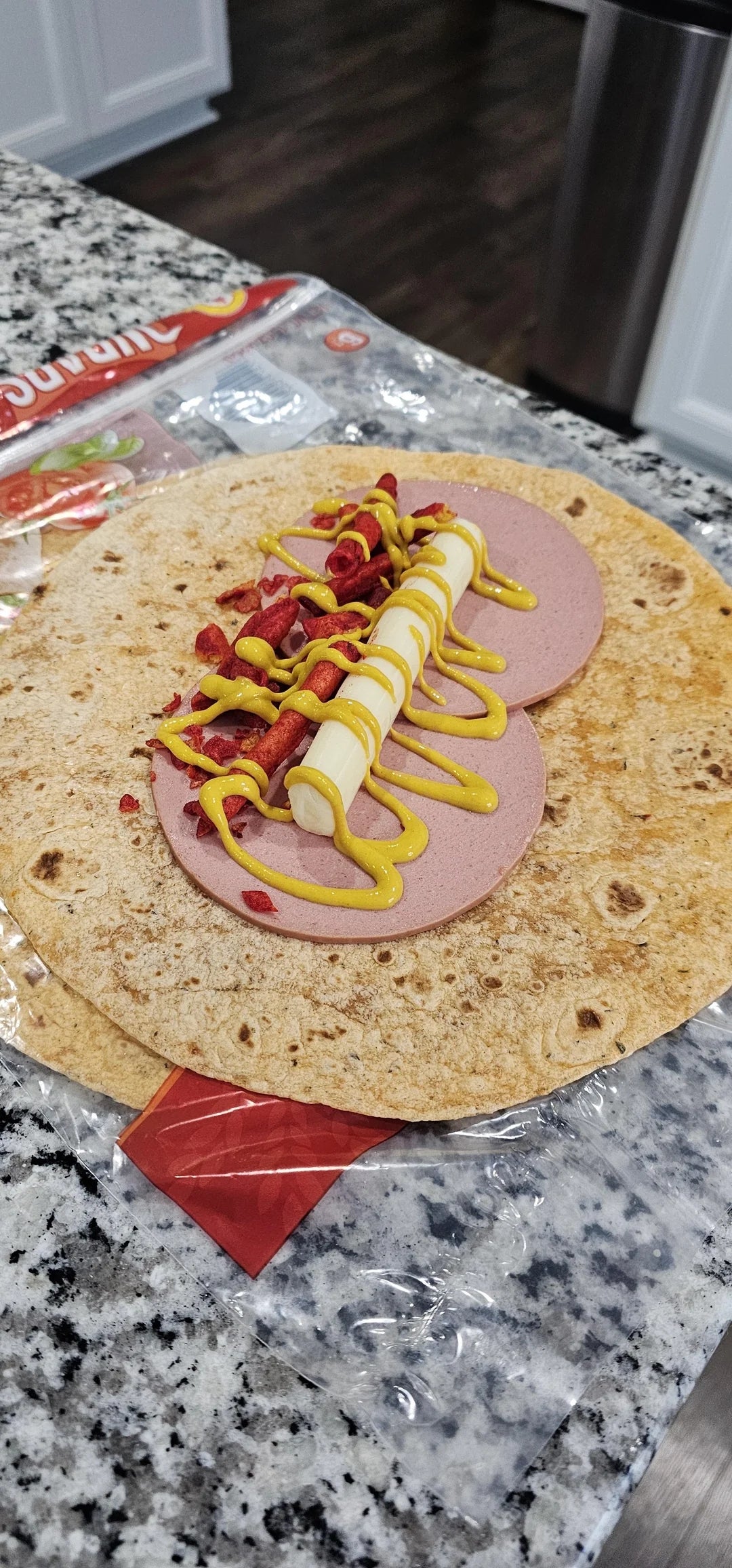 Bologna, stik keju, mustard, dan Takis di atas tortilla