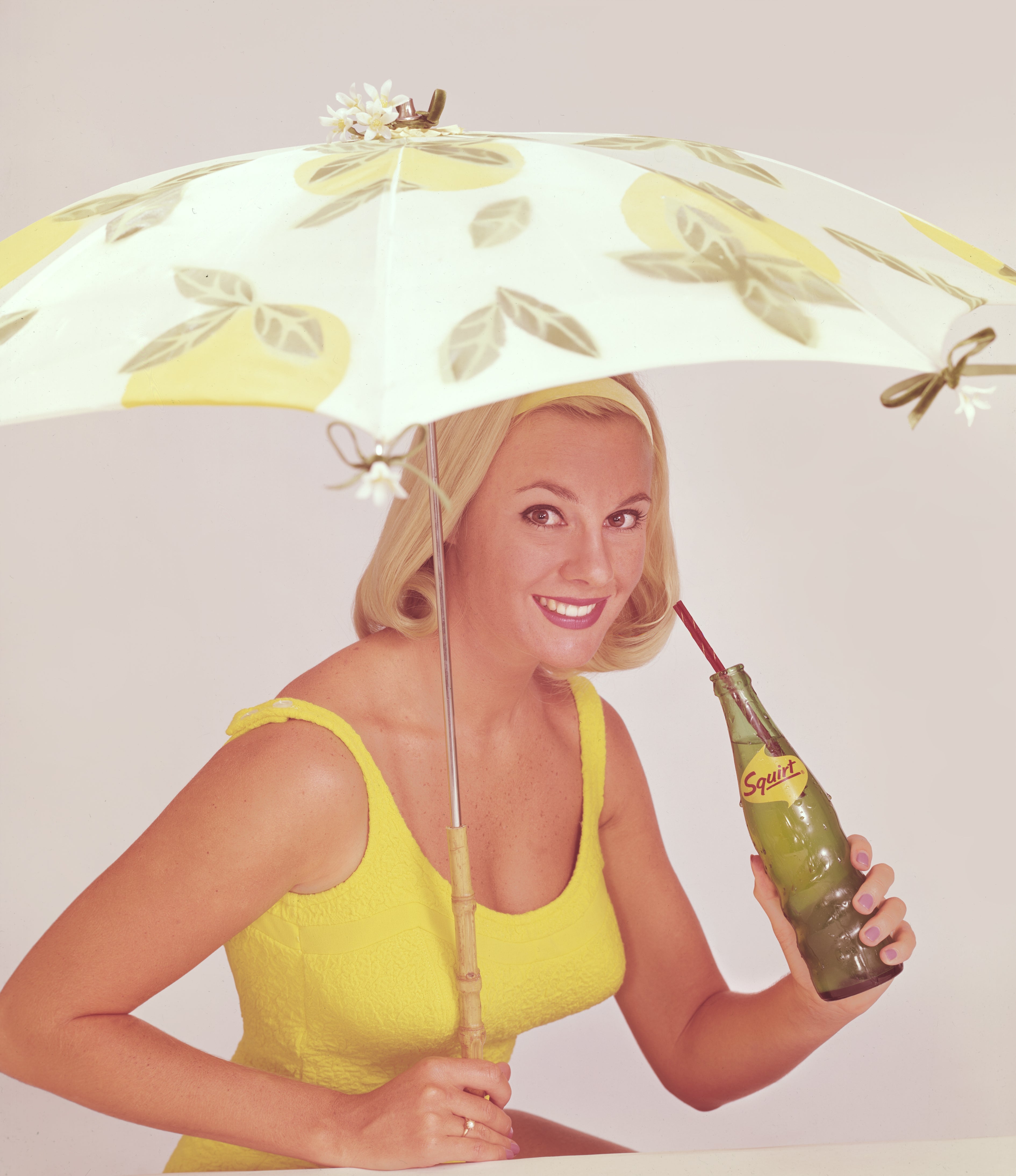 Woman successful  vintage sleeveless formal  nether  a decorated umbrella, sipping from a Squirt vessel  with a straw