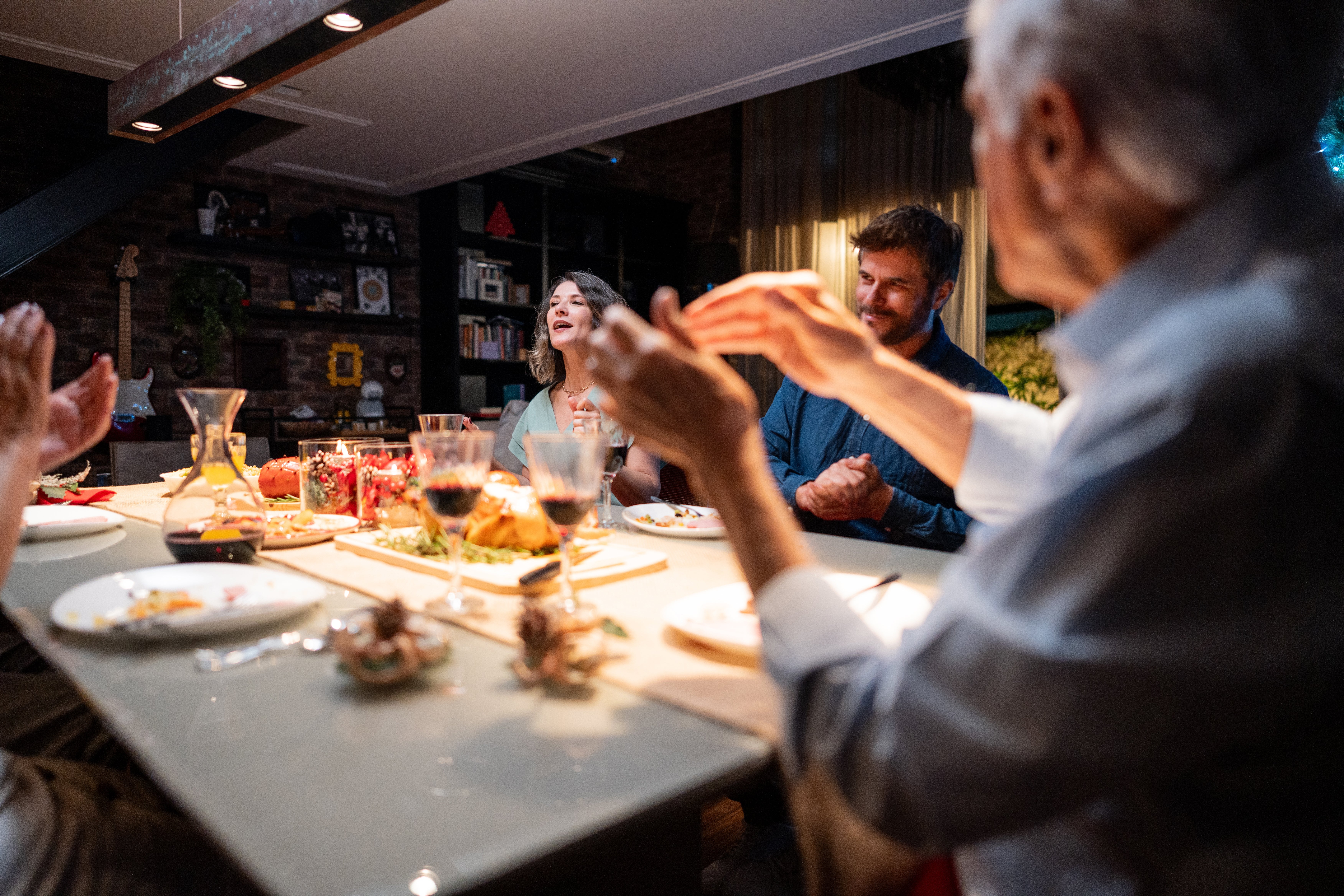 Folk nyter et festmåltid, ler og klapper rundt et spisebord dekket med mat og drikke