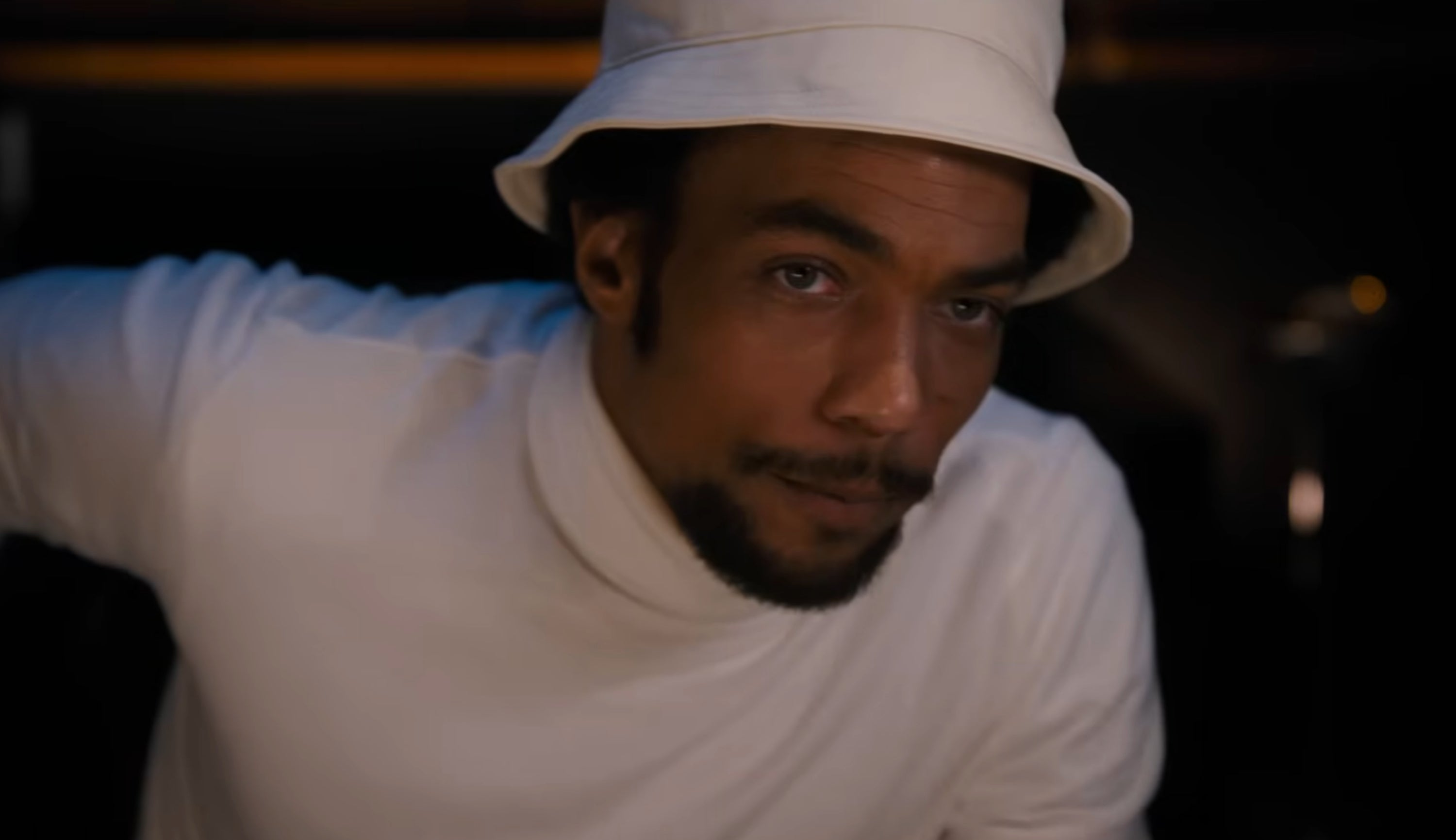 A idiosyncratic   wearing a achromatic  bucket chapeau  and turtleneck, looking focused