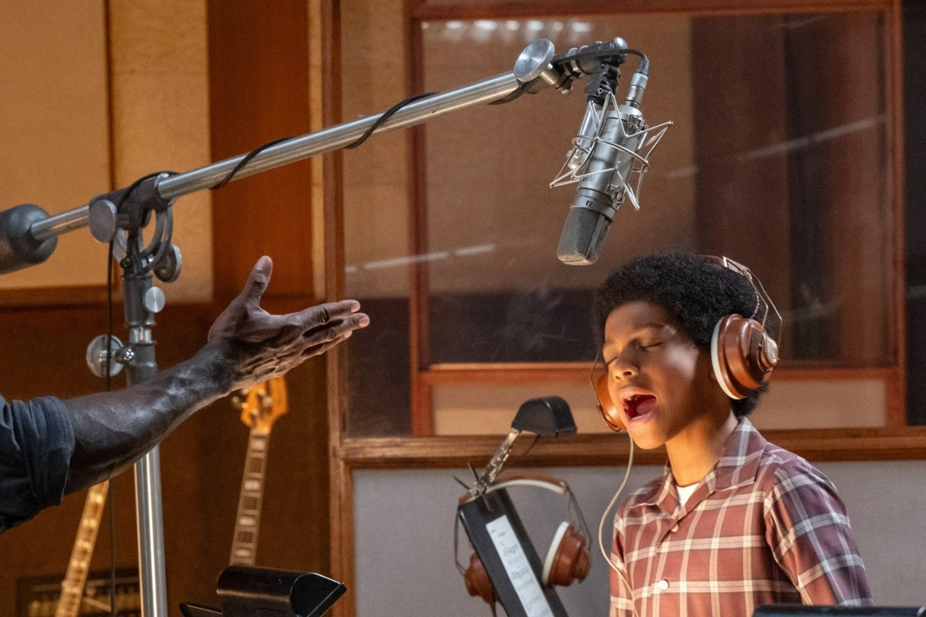 Two individuals successful  a signaling  studio, 1  big  giving guidance. The kid  is singing into a microphone, wearing headphones