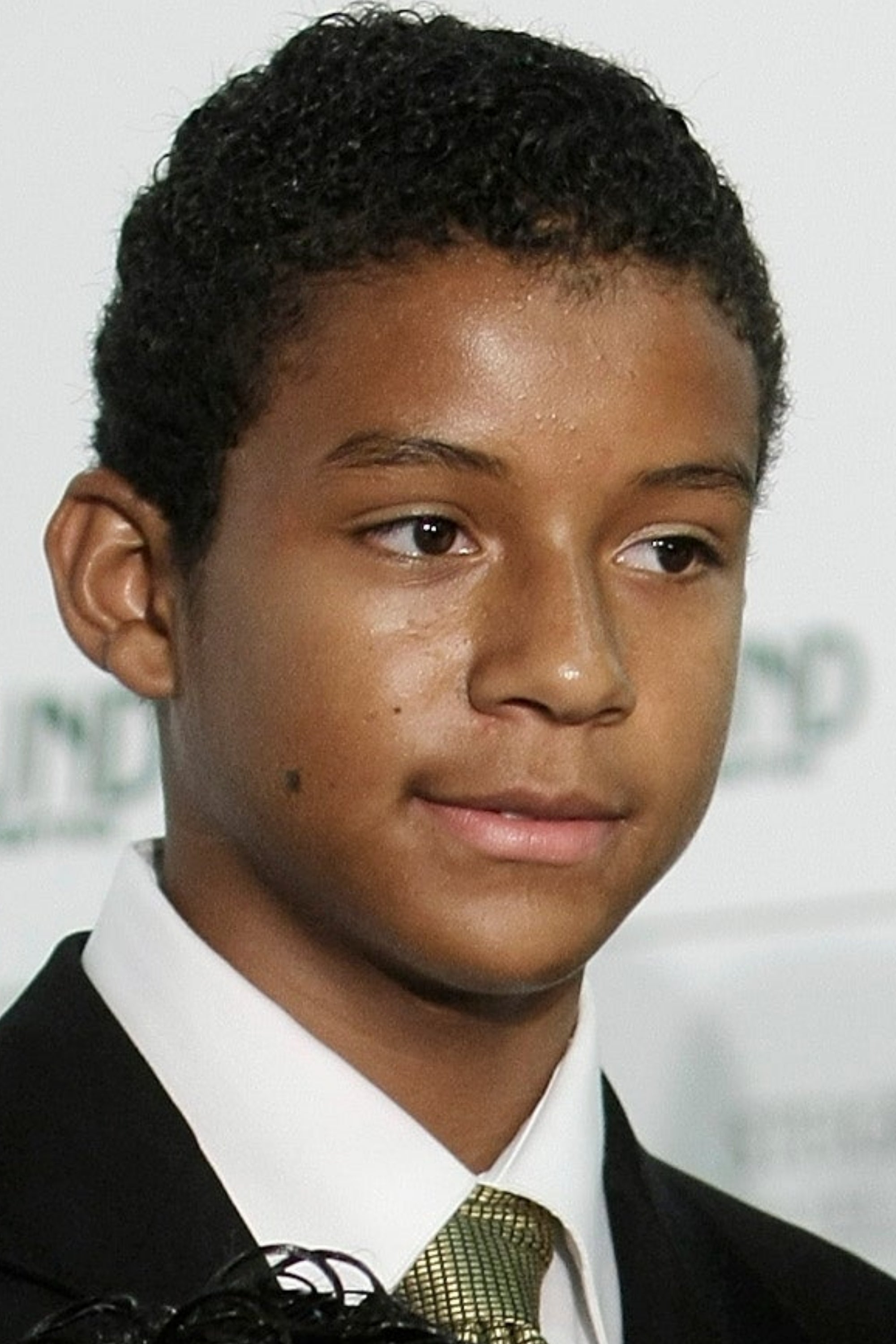 Person successful  suit   holding an award, accompanied by 2  children successful  ceremonial  attire astatine  a personage  event