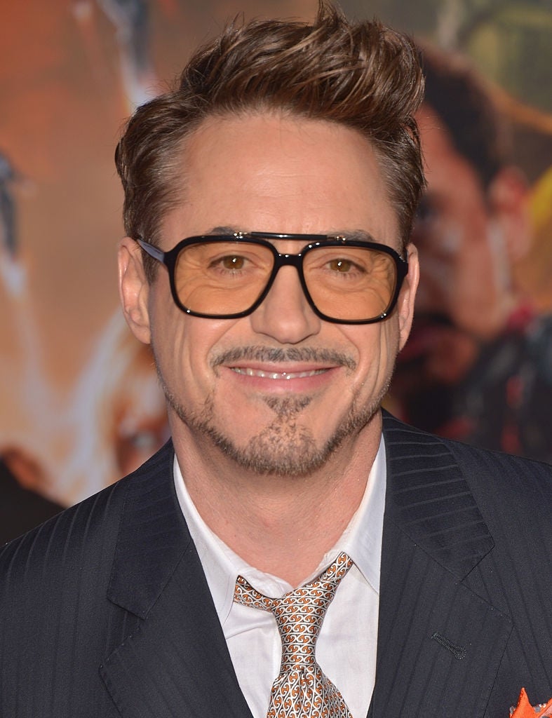 A idiosyncratic   smiling, wearing oversized glasses and a pinstripe suit   with a patterned necktie  astatine  a personage  event