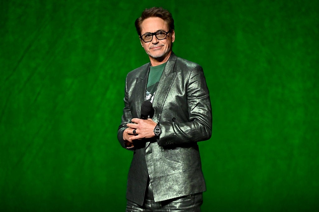 Person successful  a metallic suit   holding a microphone, lasting  against a plain background