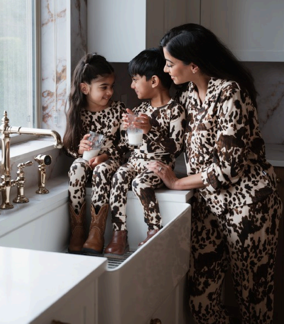 Family in matching leopard print pajamas enjoys milk together in a cozy kitchen setting
