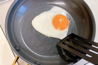 フライパンで片面が焼かれている目玉焼き。プラスチック製のフライ返しが見えている。