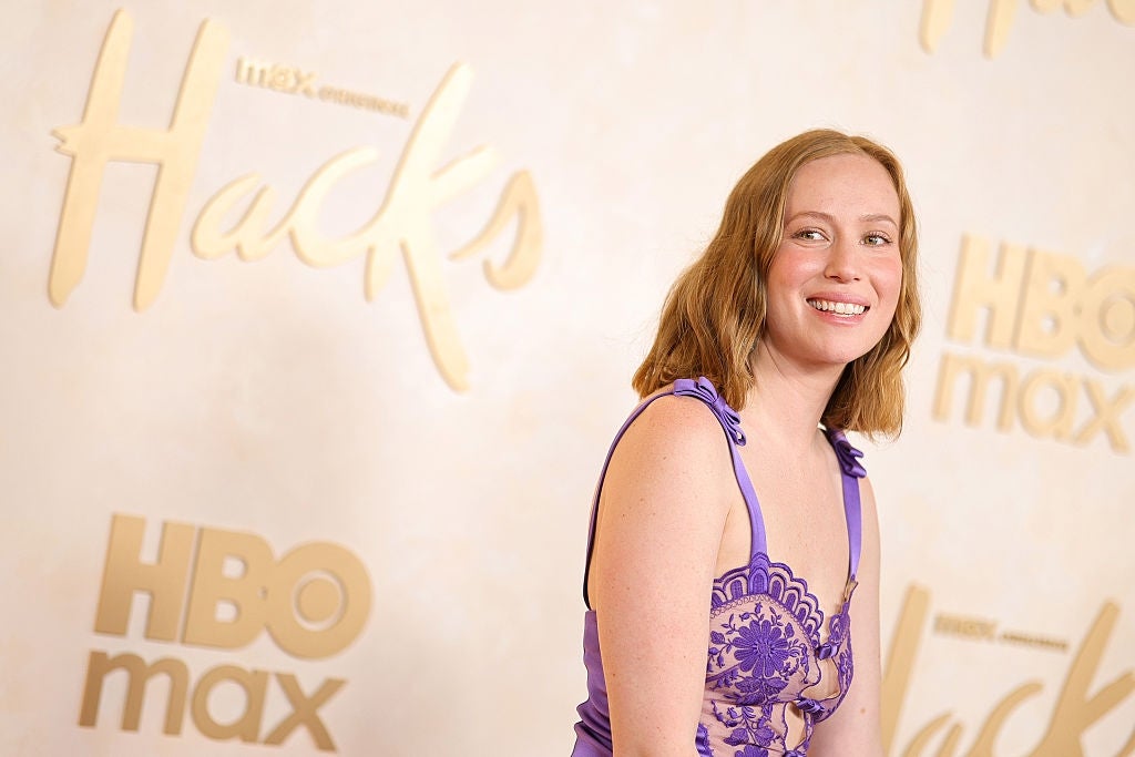 Person successful  intricate lace formal  astatine  an HBO Max lawsuit   for "Hacks," smiling for photos connected  the lawsuit   backdrop