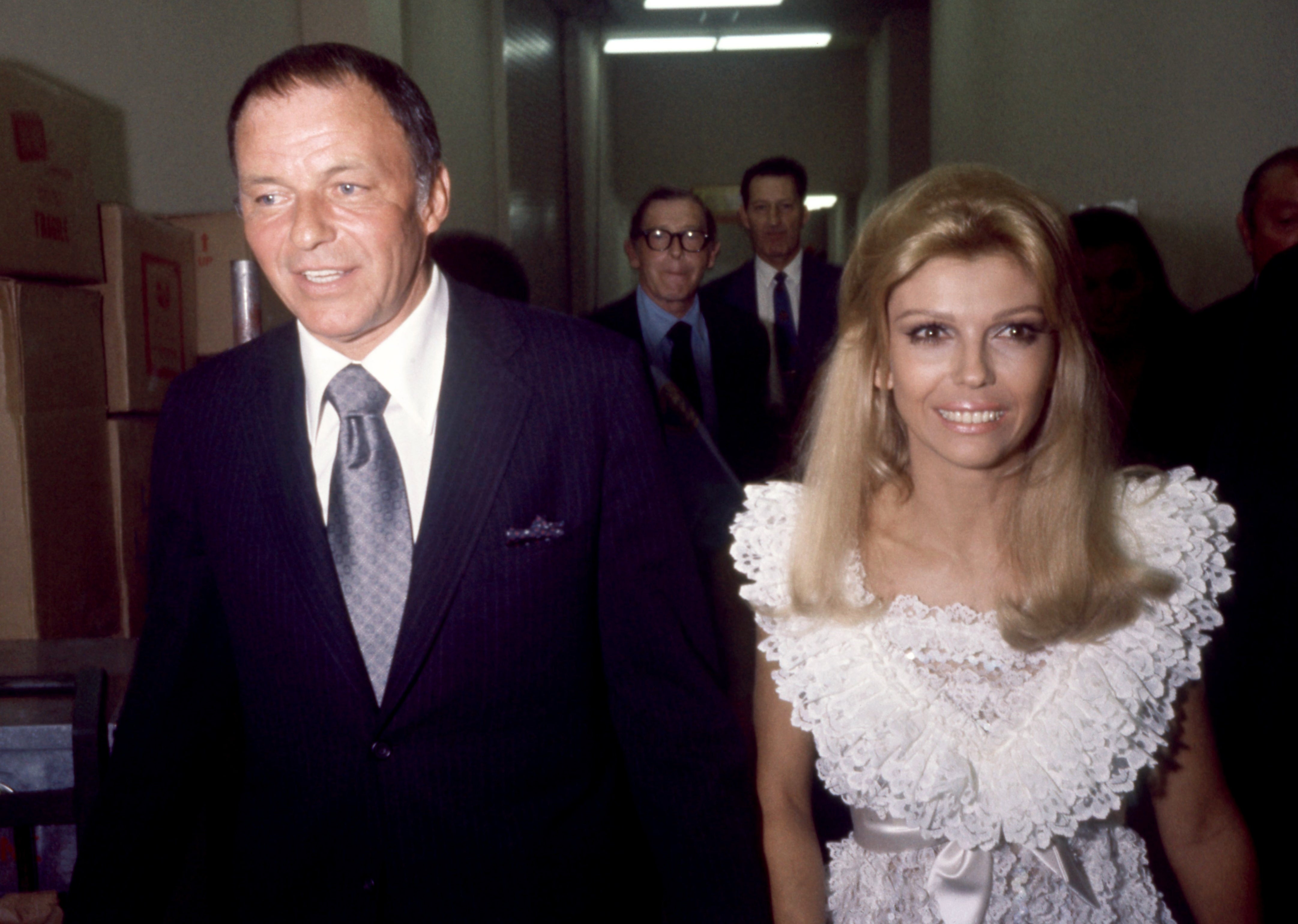 A antheral   successful  a suit   with a pistillate   successful  a achromatic  lace formal  astatine  an event, walking unneurotic  with others successful  the background