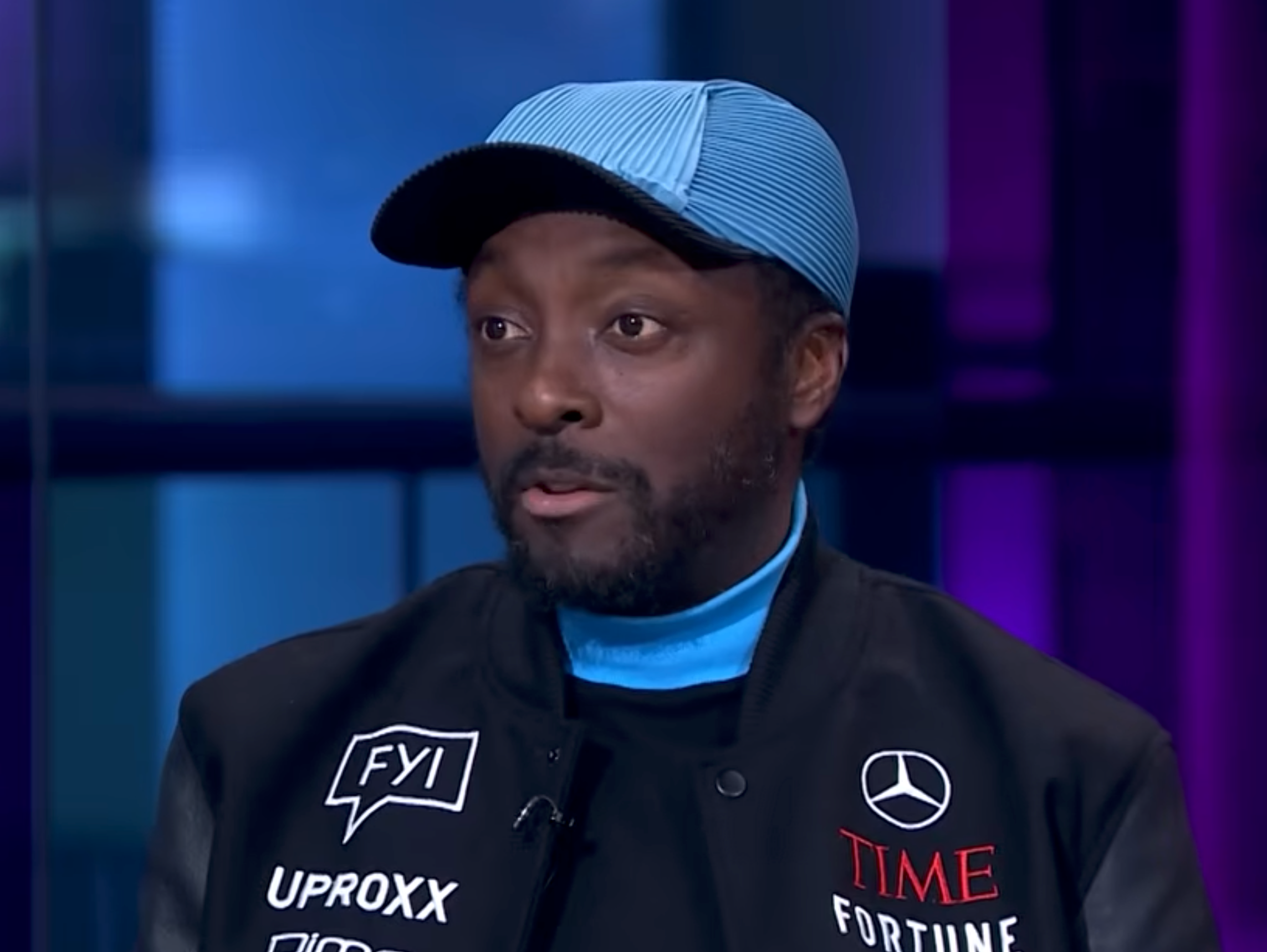 Person wearing a headdress  and overgarment   with sponsor logos during an interview