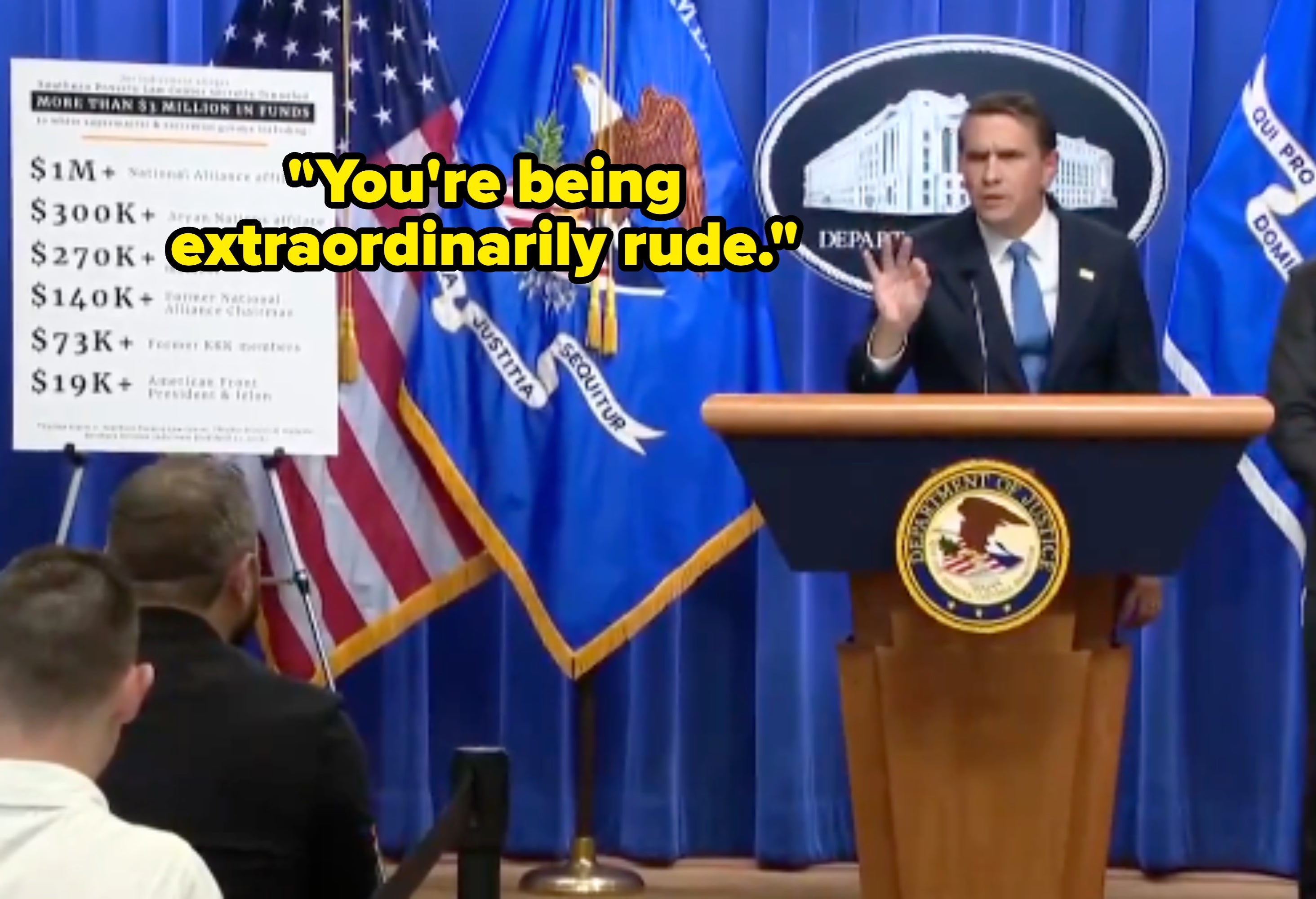 A idiosyncratic   astatine  a podium, with Department of Justice emblems, speaks during a property   event. A show  committee  lists assorted  amounts of funds