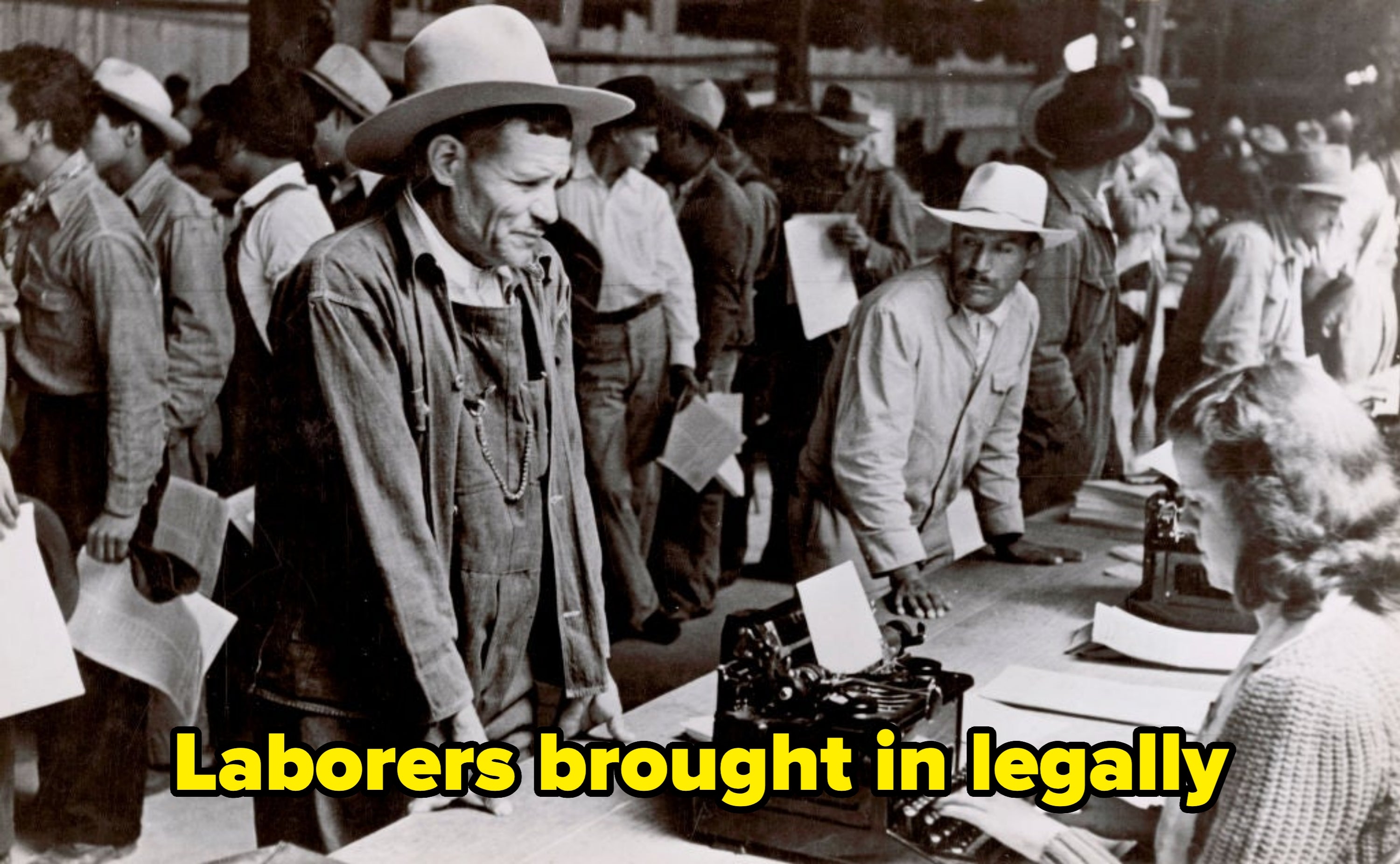 A historical  photograph  of men successful  enactment    apparel  and hats lined up   astatine  an bureau   counter, perchance  during a 1930s event
