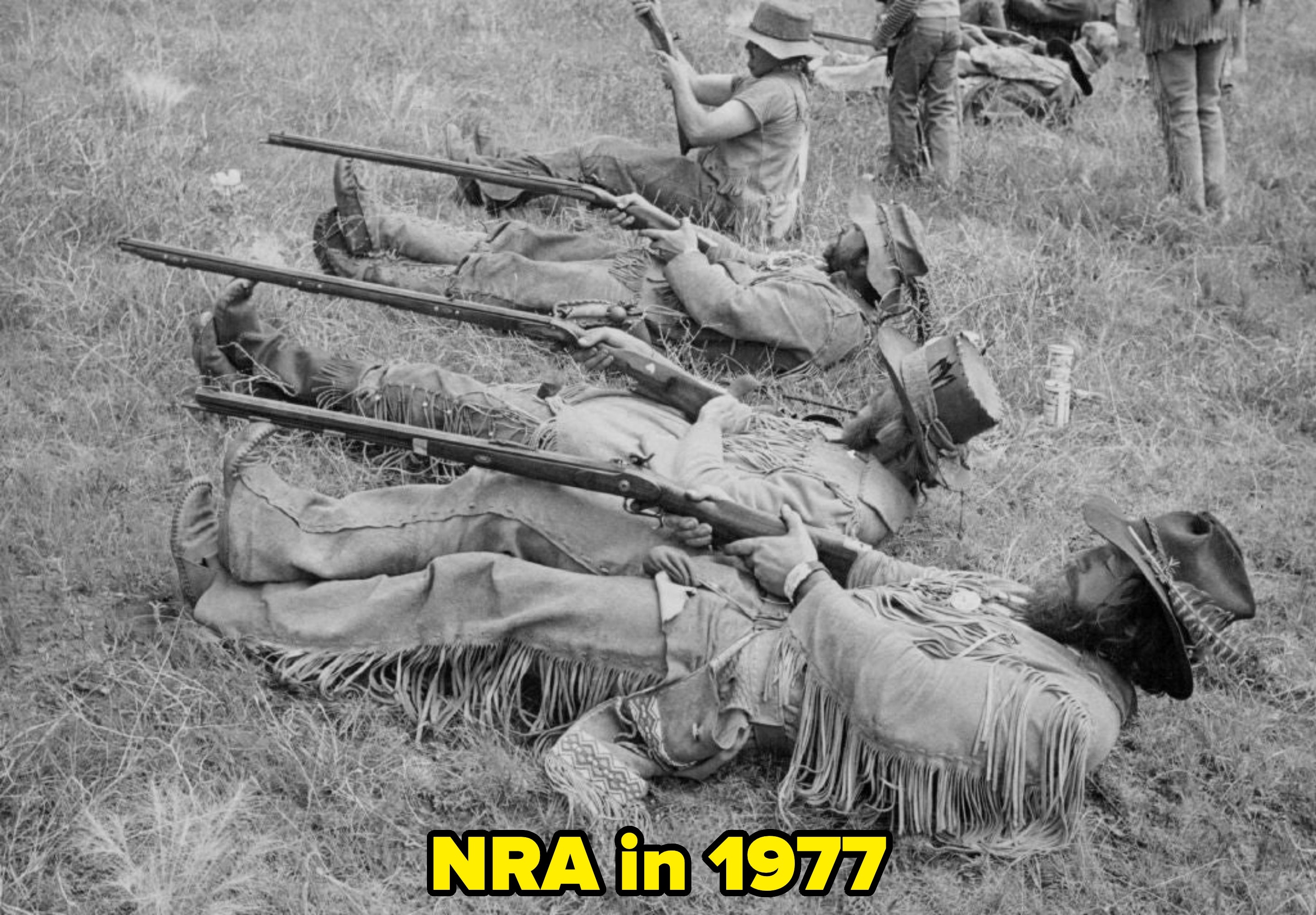 Historical reenactors successful  fringed outfits prevarication  connected  the grass, aiming rifles arsenic  portion  of a conflict  country   recreation