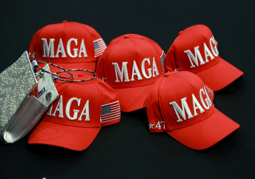 Fem røde baseballcapser med "MAGA" tekst og amerikansk flagg-lapper vist på en overflate
