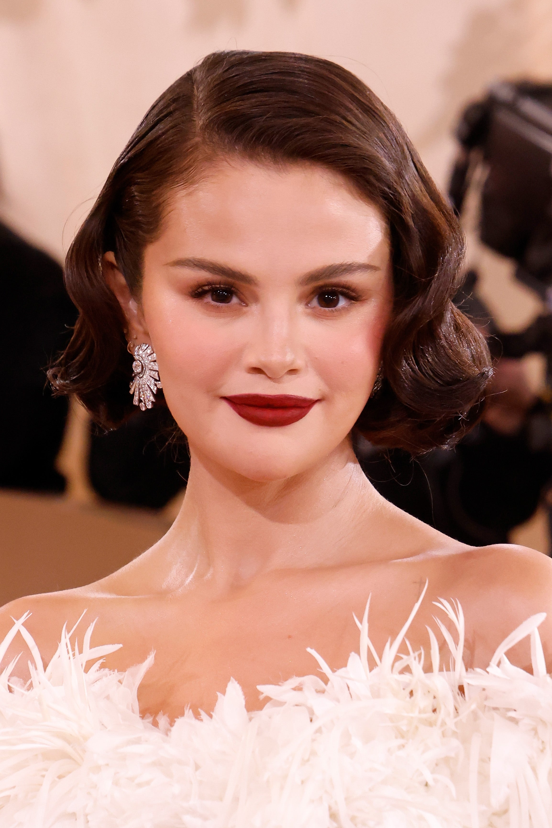 Selena Gomez connected  a reddish  carpet wears an elegant feathered gown and connection    earrings, with styled abbreviated  hairsbreadth  and bold makeup