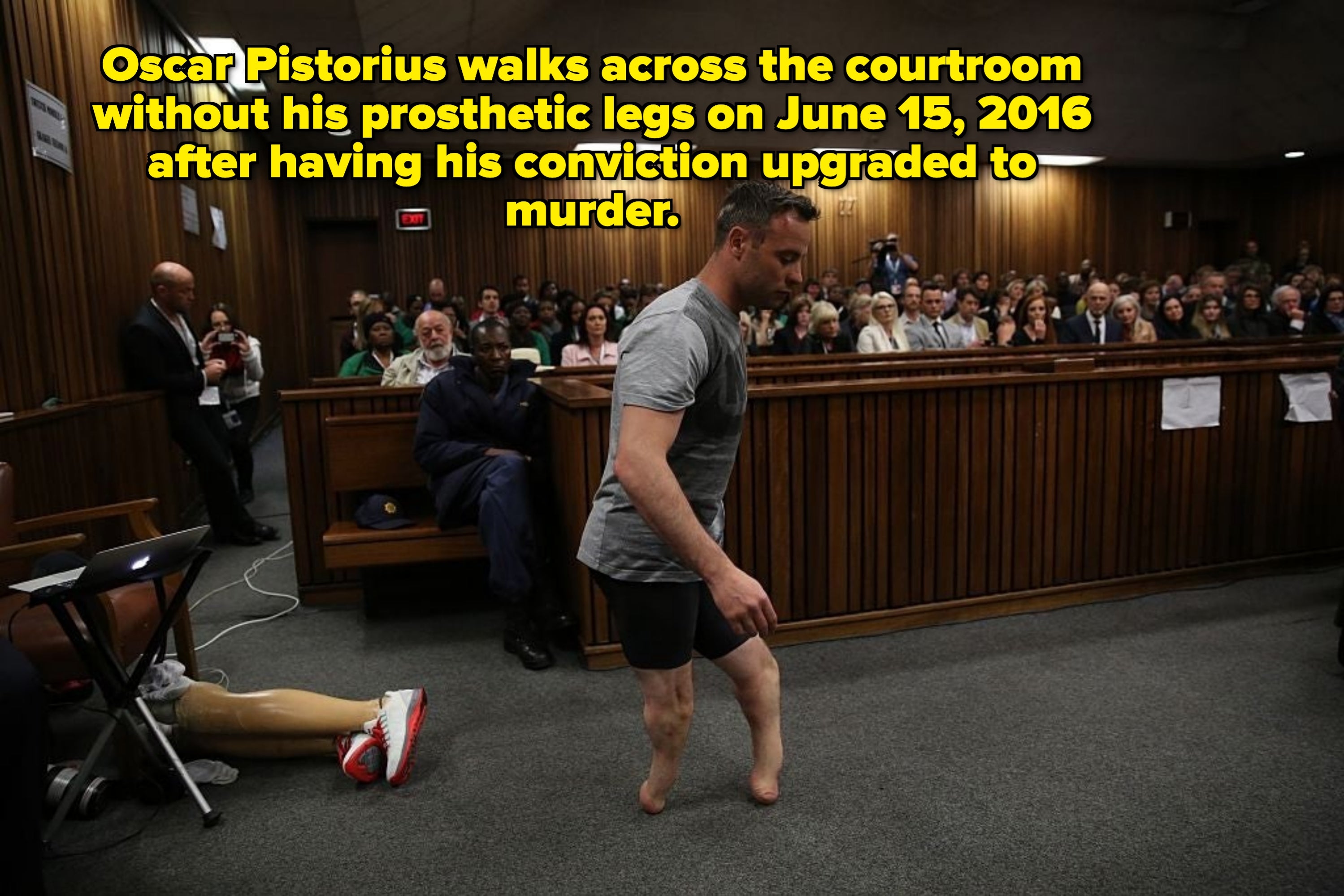 An jock  with prosthetic legs walks successful  a courtroom setting, surrounded by an assemblage  and ineligible  professionals