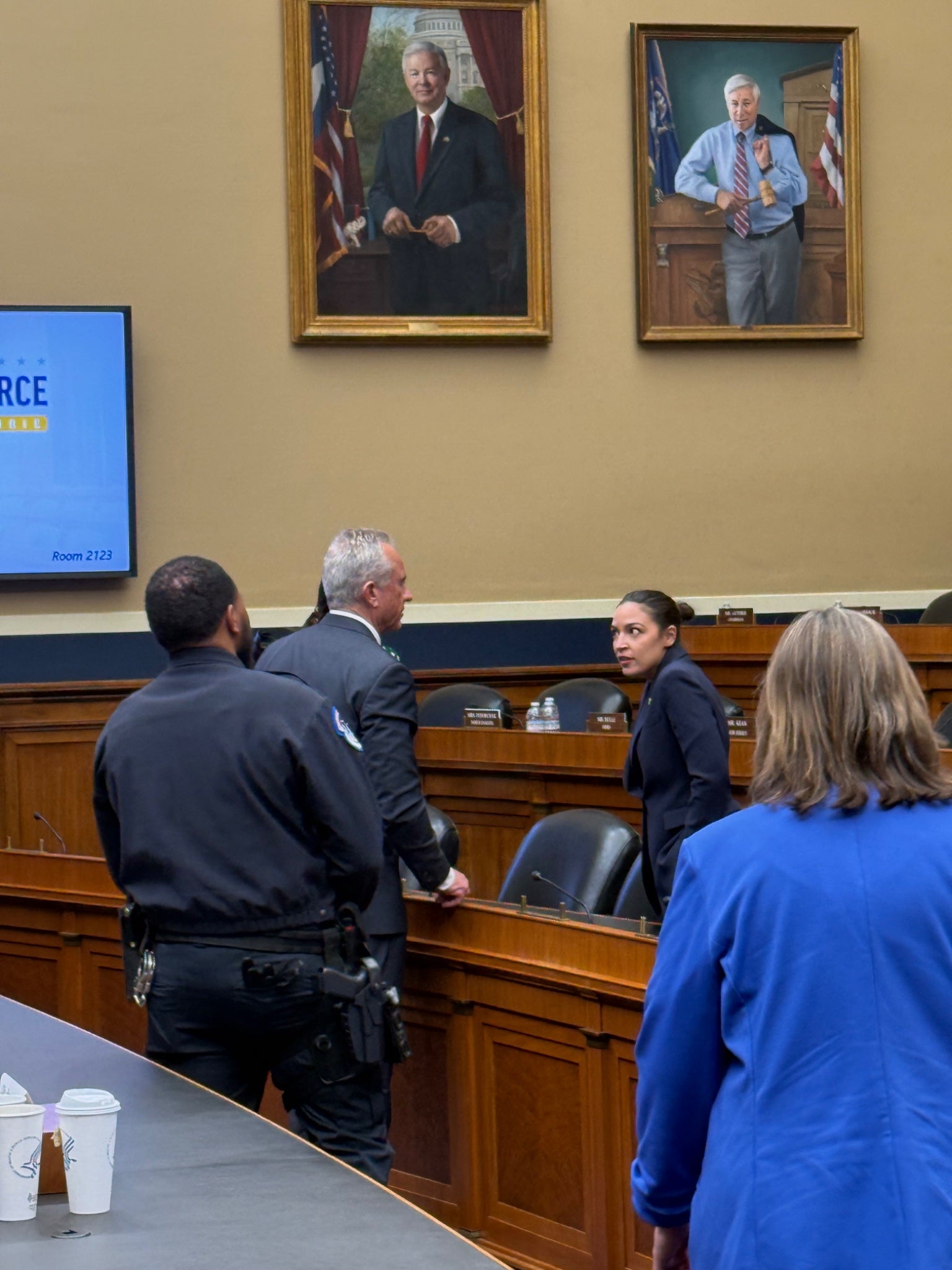 People successful  a courtroom setting, engaging successful  discussion. Walls show  portraits and a surface  shows substance   but details are unclear