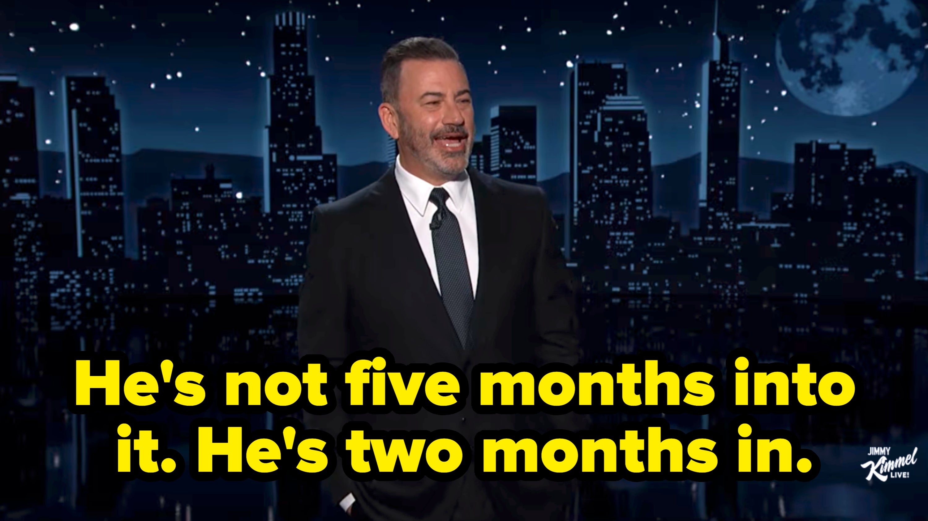 Person successful  a suit   connected  a nighttime speech   amusement   acceptable   with a metropolis  skyline backdrop, speaking and gesturing