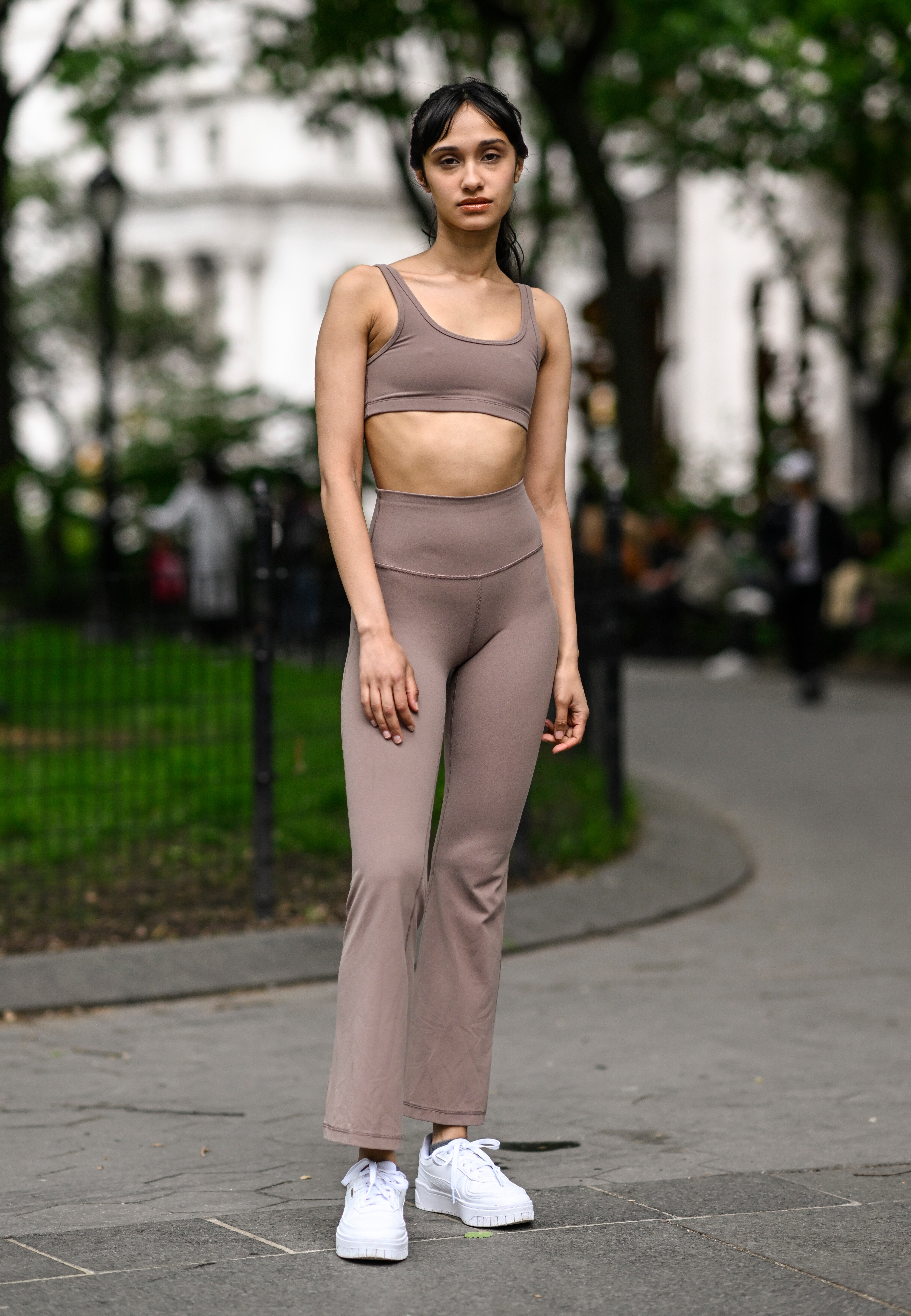 Person successful  a parkland  wearing a sleeveless harvest  top, high-waisted pants, and sneakers. The outfit is casual and comfortable