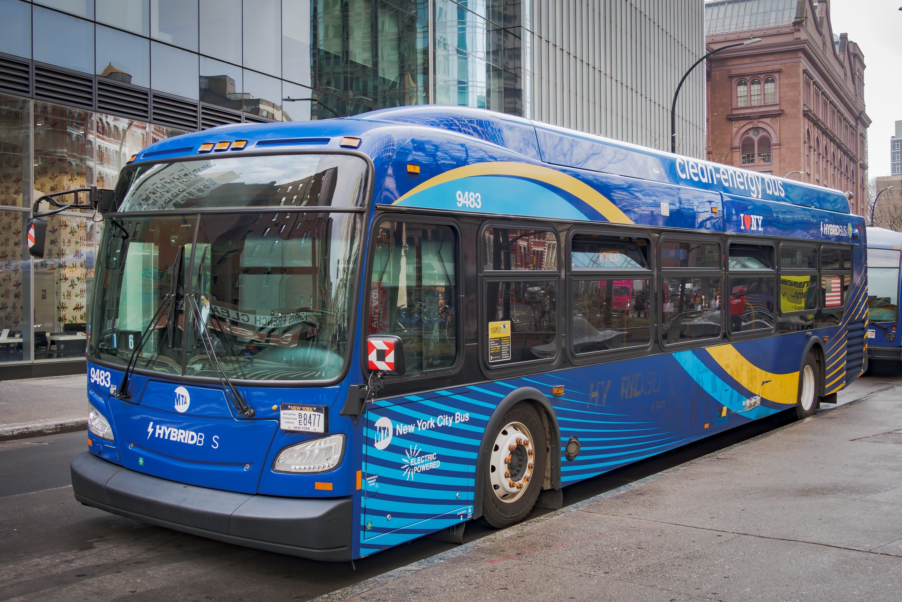New York City hybrid autobus  parked connected  a street, surrounded by modern   buildings