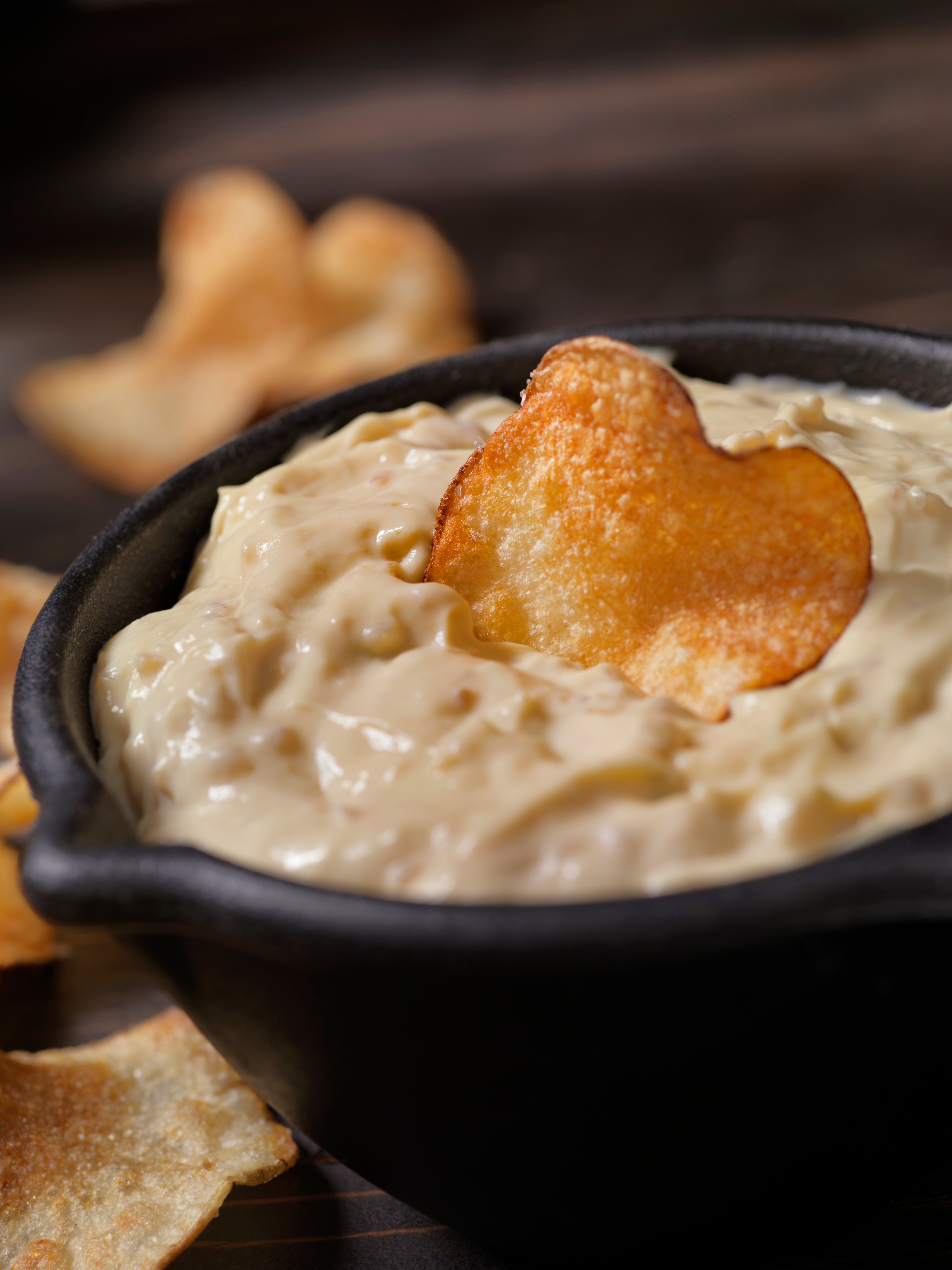 Potato spot   dipped successful  creamy bulb  dip successful  a bowl. Other chips are scattered around