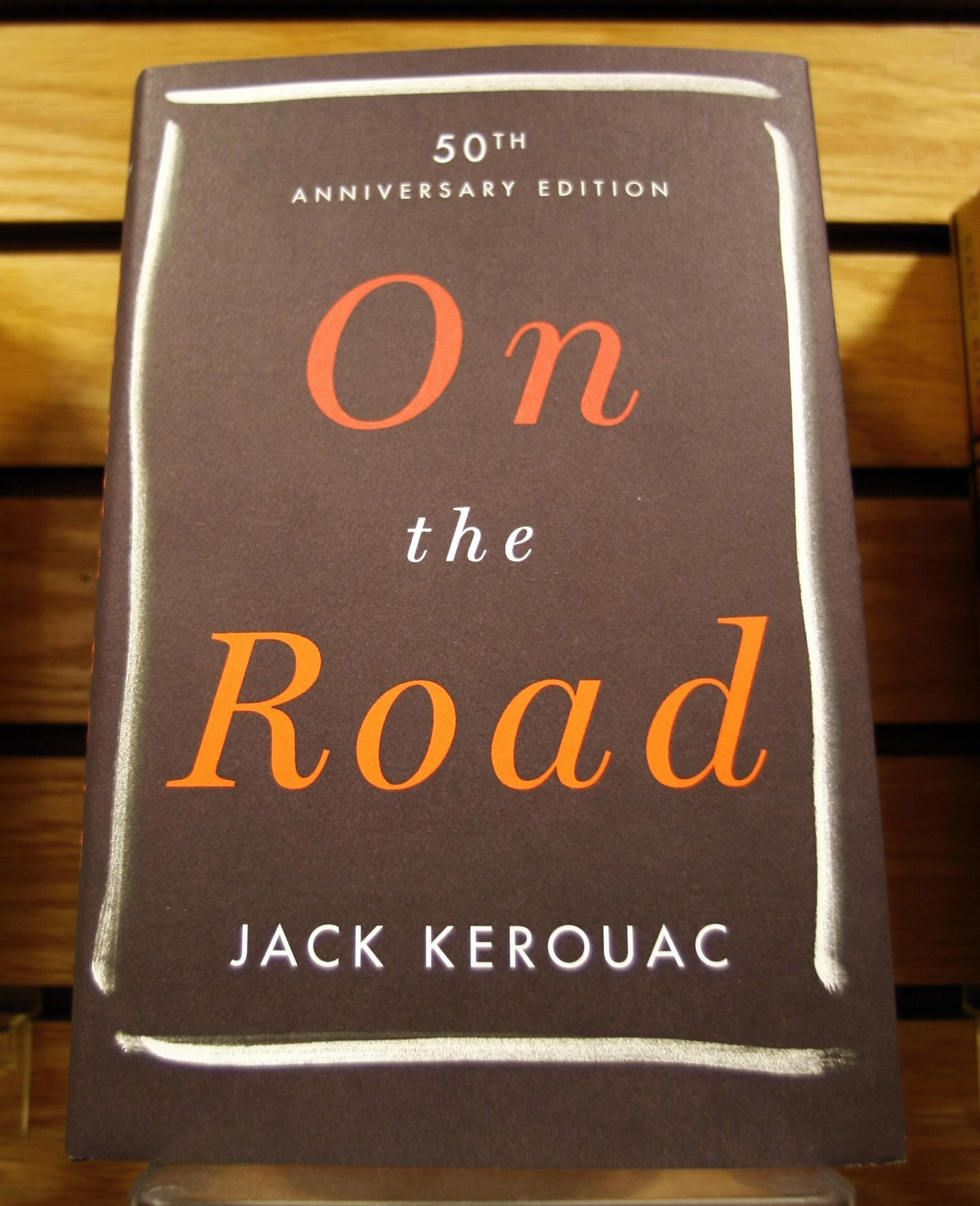 Cover of "On the Road" by Jack Kerouac, 50th Anniversary Edition, displayed connected  a shelf