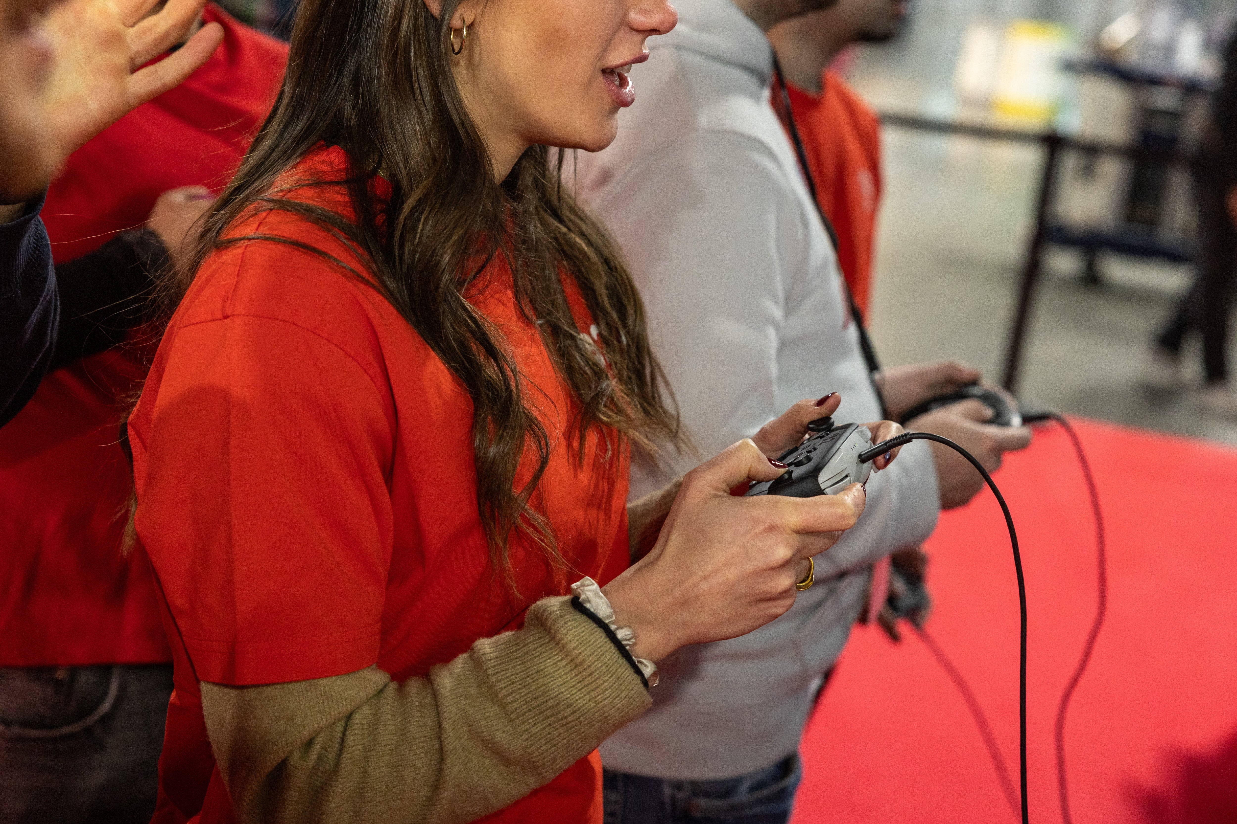 People playing video games astatine  an event, holding controllers with focused expressions