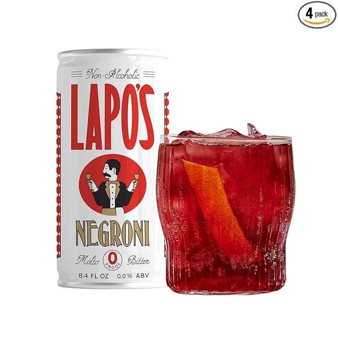 Can of non-alcoholic Lapo's Negroni beside a glass filled with ice and an orange peel. The can features a vintage-style illustration