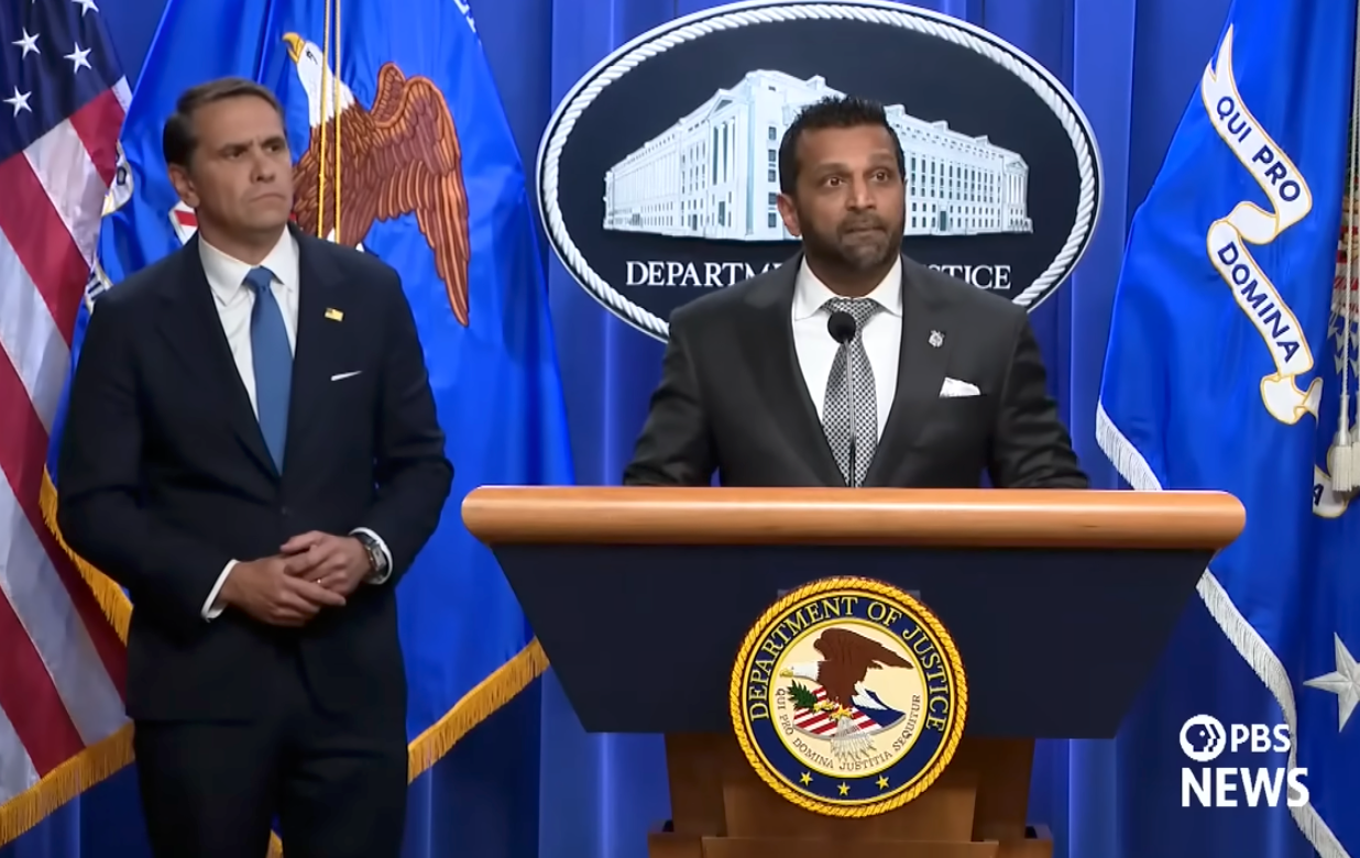 Two officials astatine  a Department of Justice podium during a property   briefing, with DOJ seal visible
