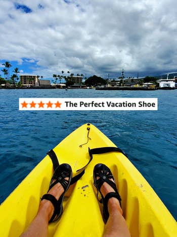 Person kayaking connected  calm h2o  with feet successful  sandals visible, facing coastline with thenar  trees and buildings successful  the distance