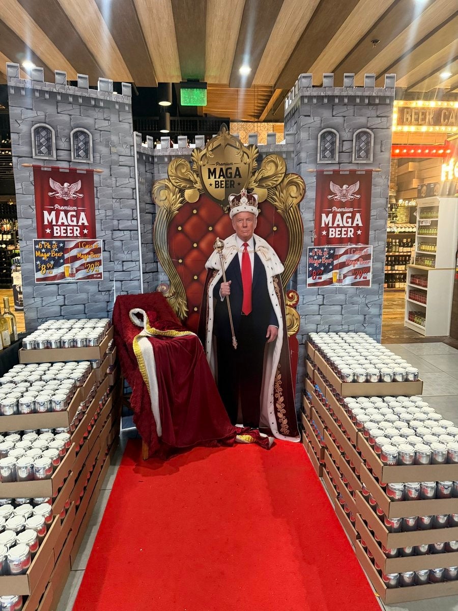 Cardboard cutout of a antheral   dressed arsenic  a king, with a reddish  carpet and throne, surrounded by brew  cans displayed successful  a store