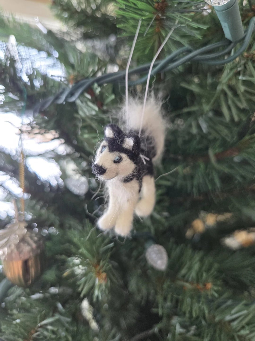 A fluffy canine  ornament hangs connected  a Christmas histrion   branch