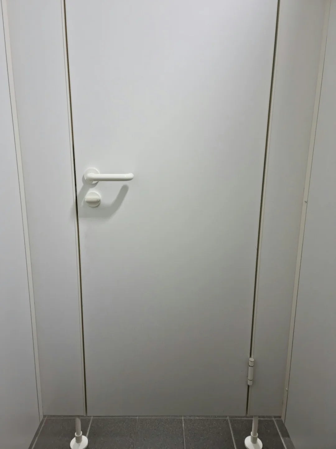 A closed, plain bath  stall doorway  with a grip  is shown from the outside