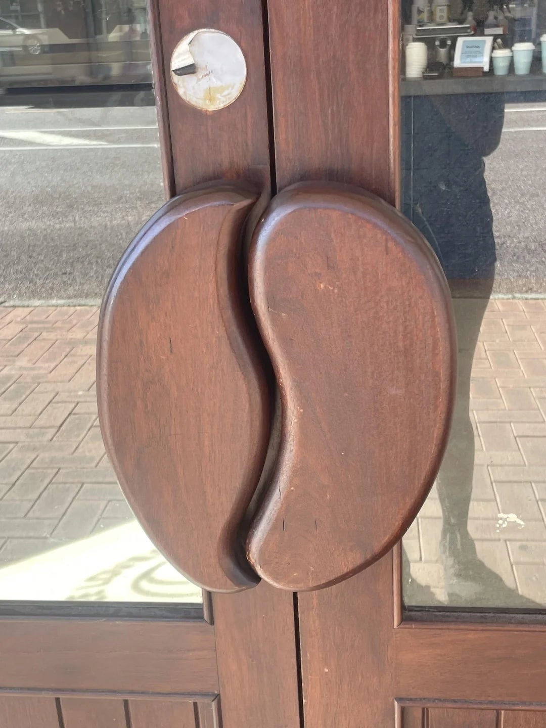 Wooden doorway  handles shaped similar  java  beans connected  a solid  door, seen from outside