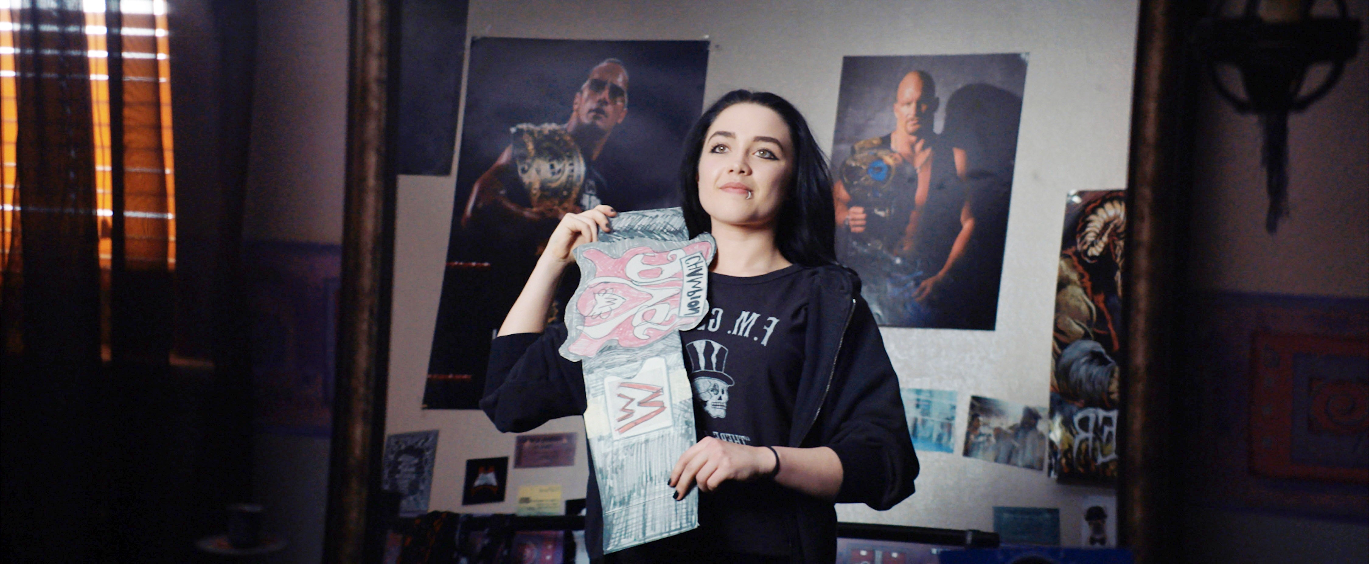 Person holding a wrestling championship belt in a room with wrestling posters on the walls