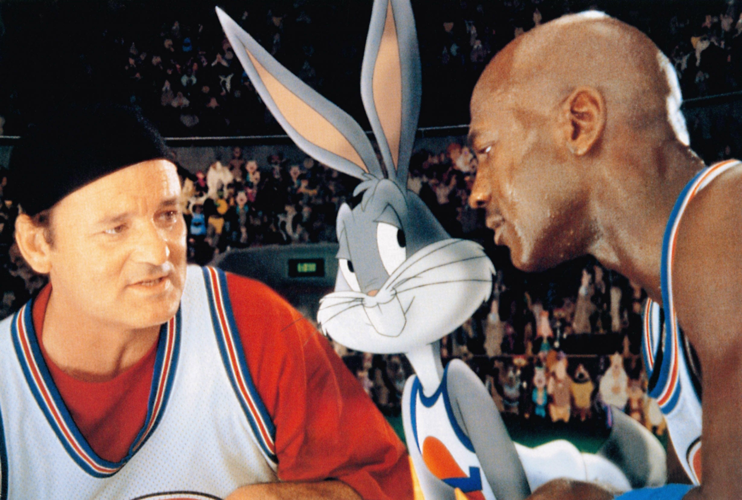 Actor in a beanie, Bugs Bunny, and basketball player in jerseys converse on a basketball court scene reminiscent of "Space Jam"