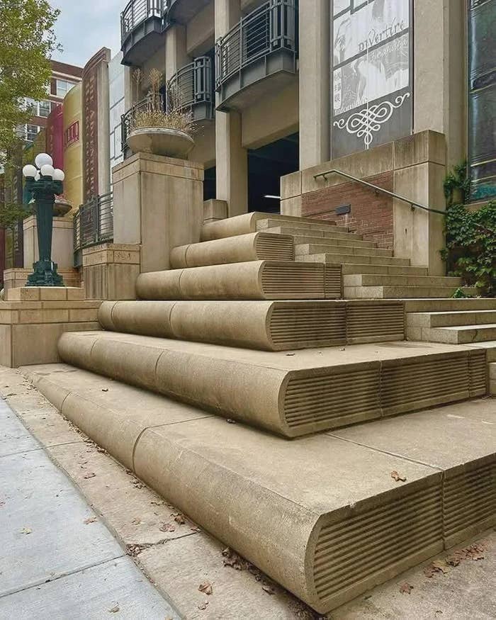 Building entranceway  with stairs designed to lucifer   stacked books, starring  to a modern   facade