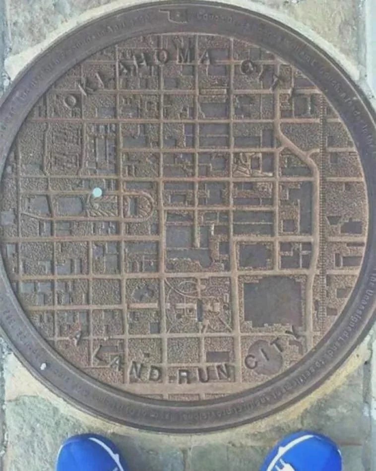 Manhole screen  depicting a elaborate  representation  of Oklahoma City with a person's bluish  shoes disposable   astatine  the bottom