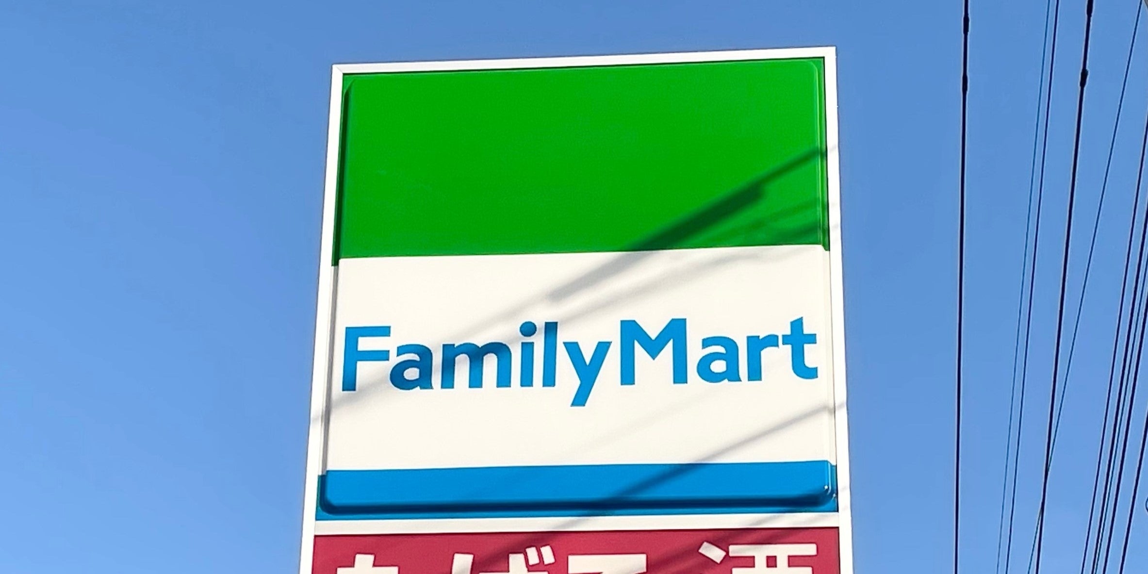 ファミリーマートの看板が青空の下に立っている。