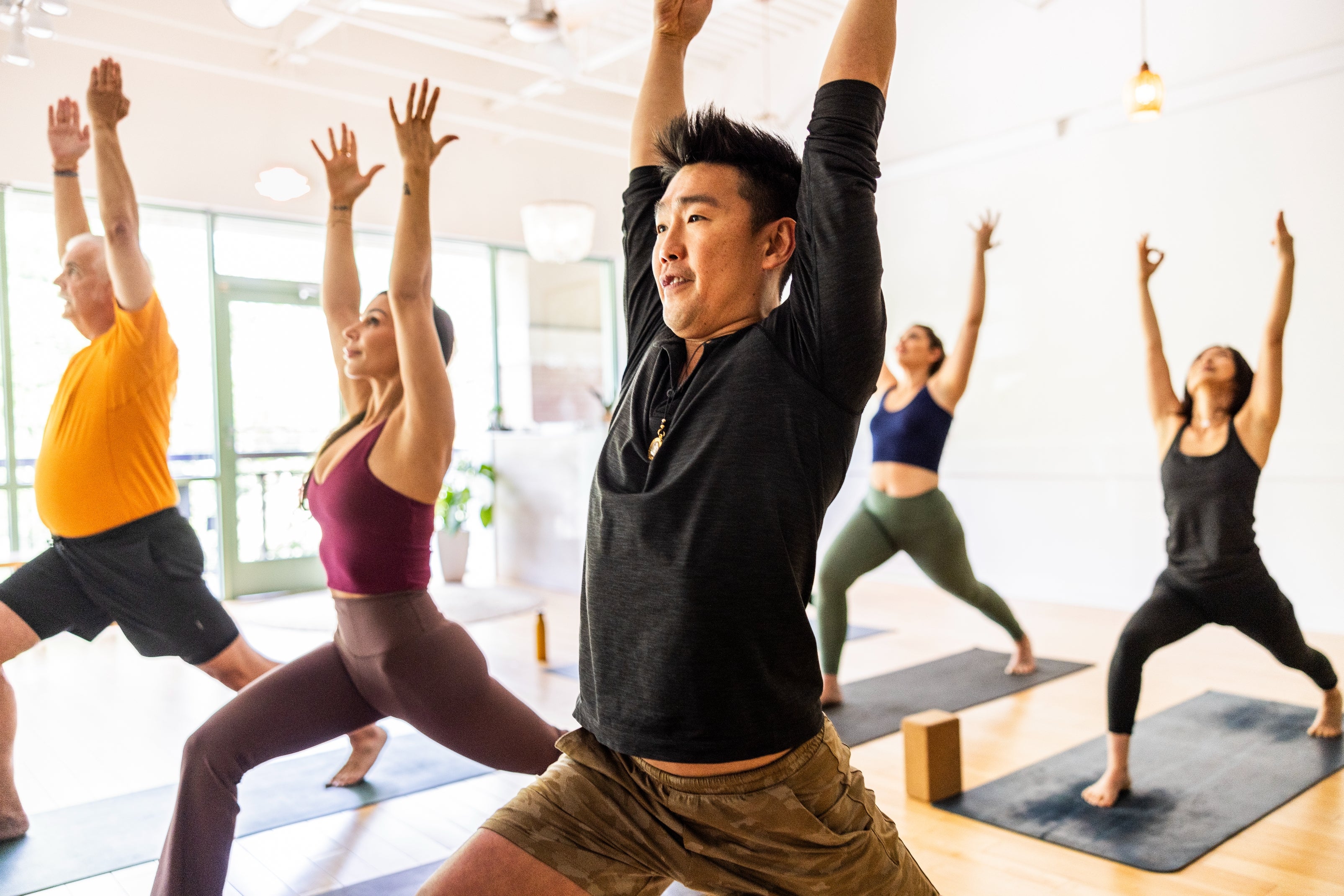 A radical  of divers  radical   practicing yoga indoors, performing a warrior airs  with arms raised, focused connected  equilibrium  and posture