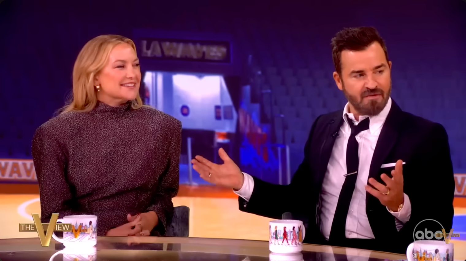 Two radical   seated connected  a speech   amusement   set, engaged successful  conversation. One is wearing a ceremonial  suit, the different   a high-neck textured dress