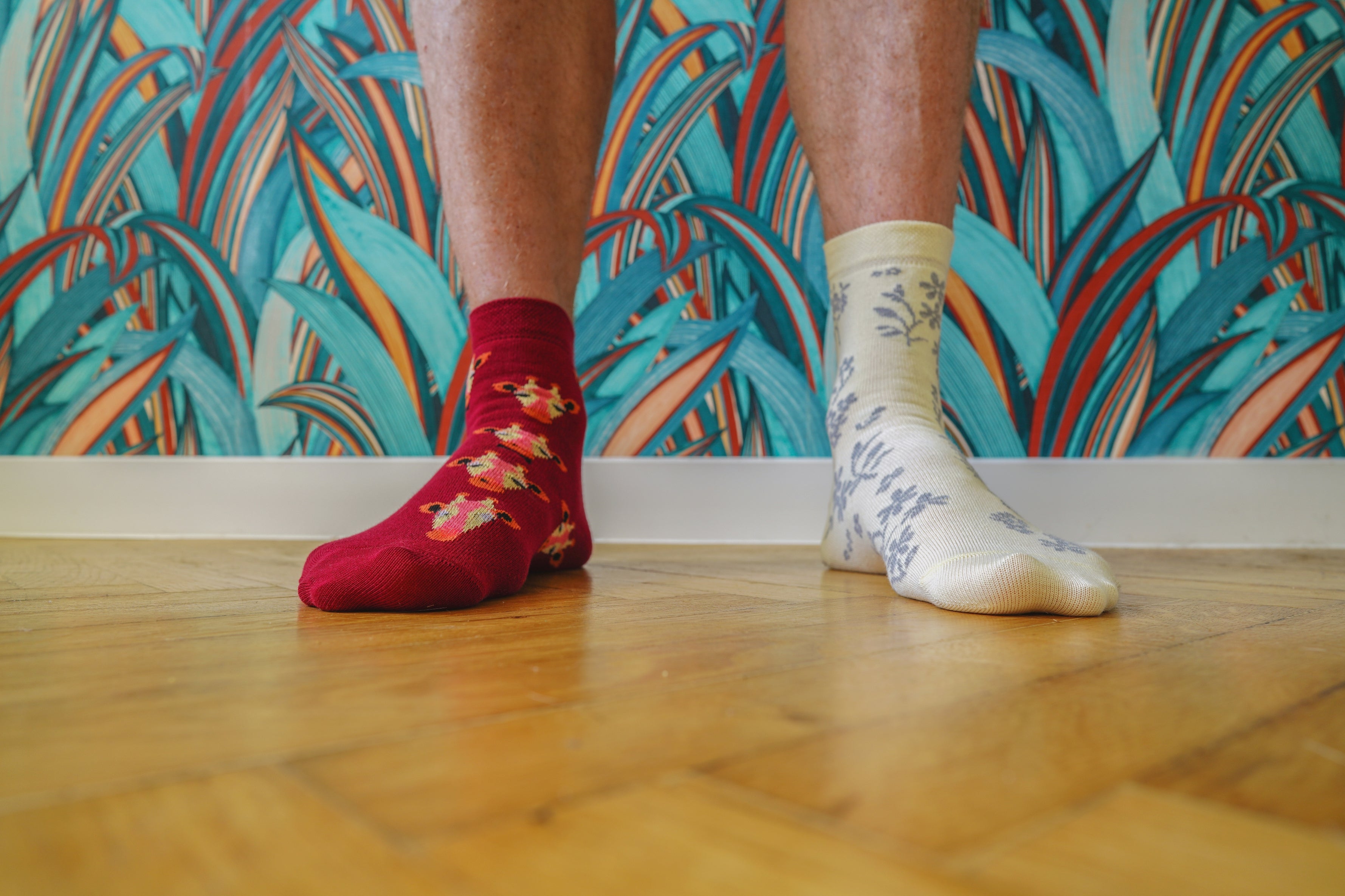 Person wearing mismatched socks, 1  with a floral signifier   and the different   with a elemental  design, lasting  connected  a woody  floor