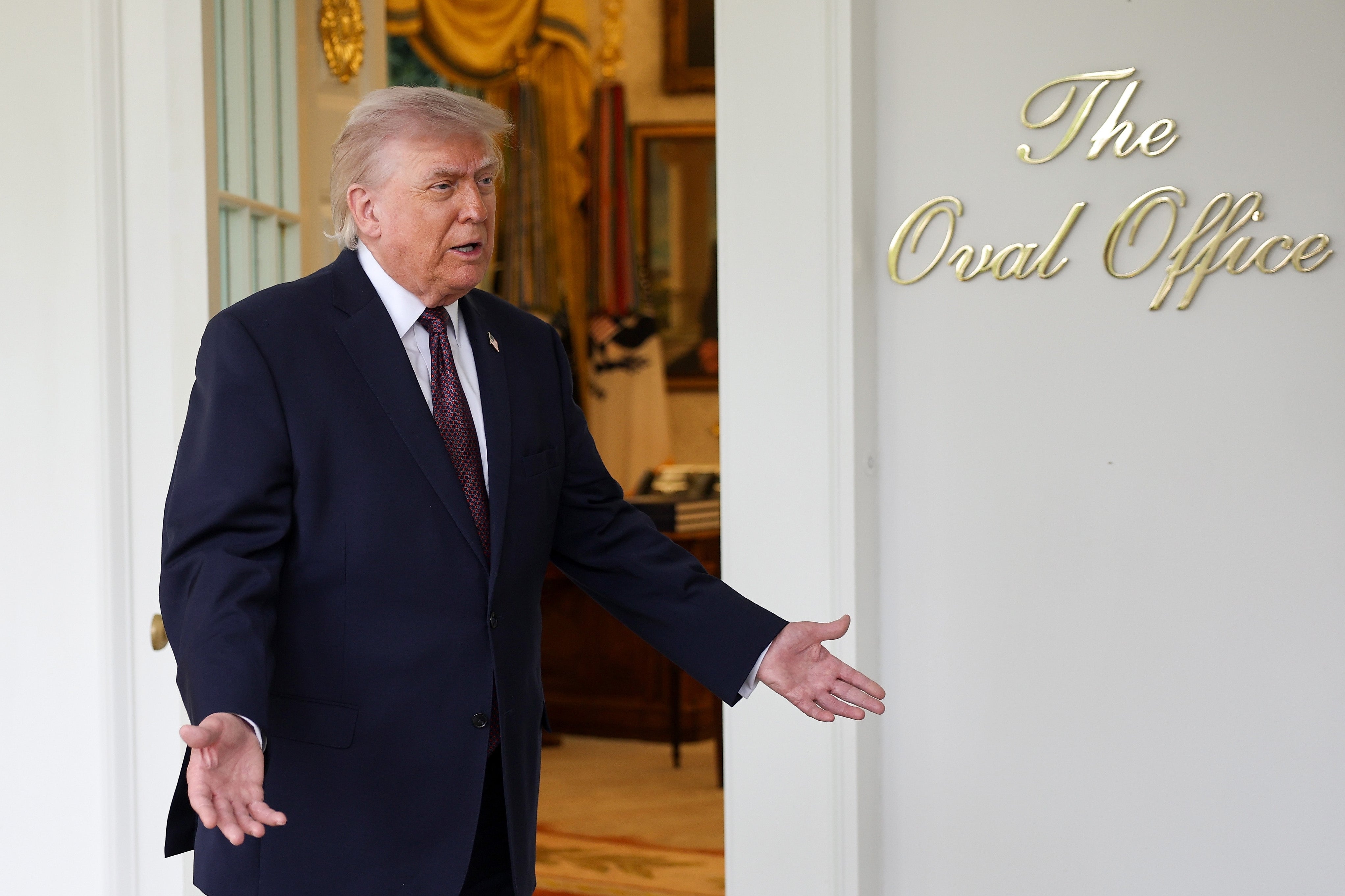 A idiosyncratic   successful  a suit   gestures with some  hands successful  beforehand   of a doorway  labeled "The Oval Office."