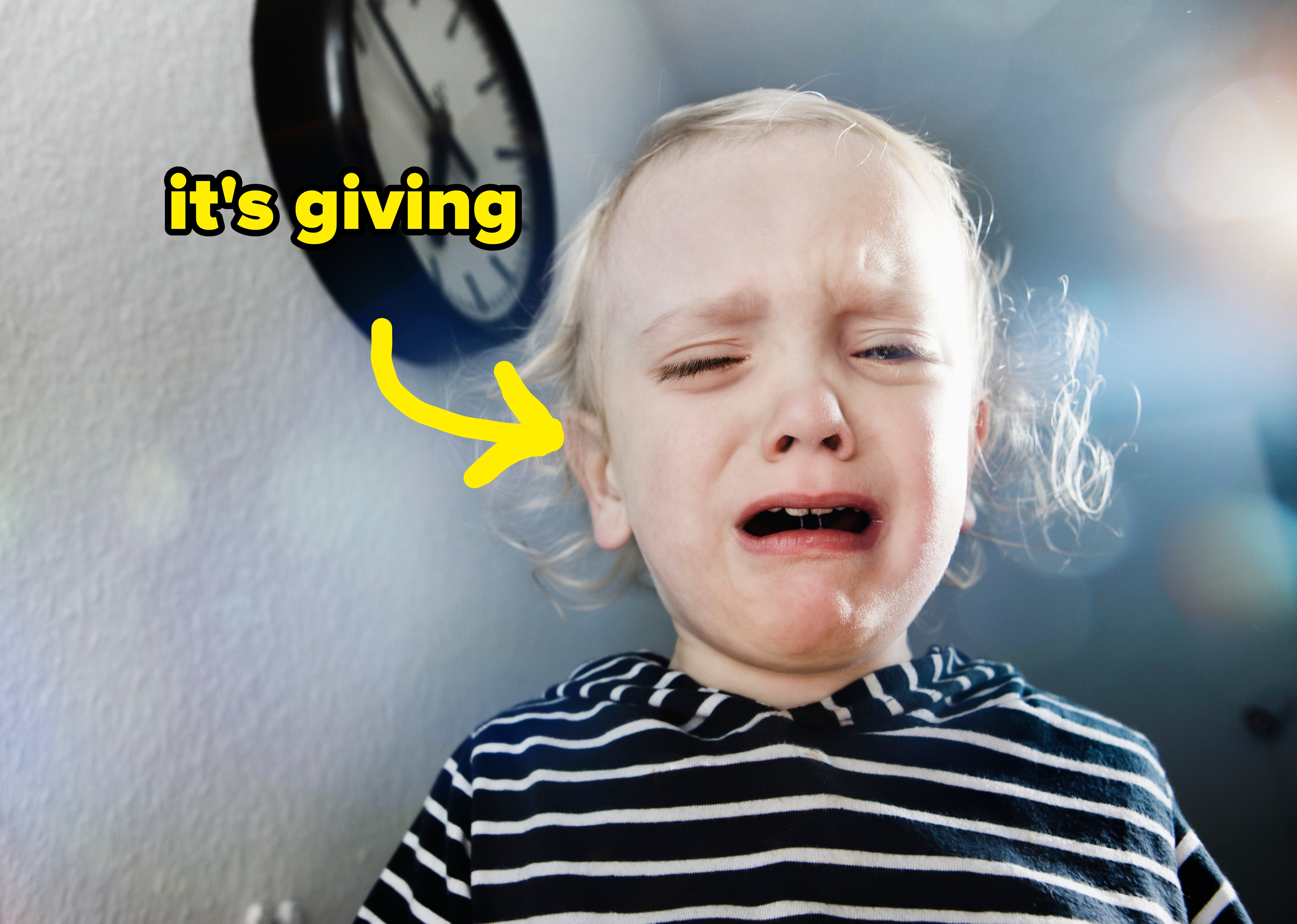 A young kid  successful  a striped garment  cries successful  beforehand   of a partition  clock