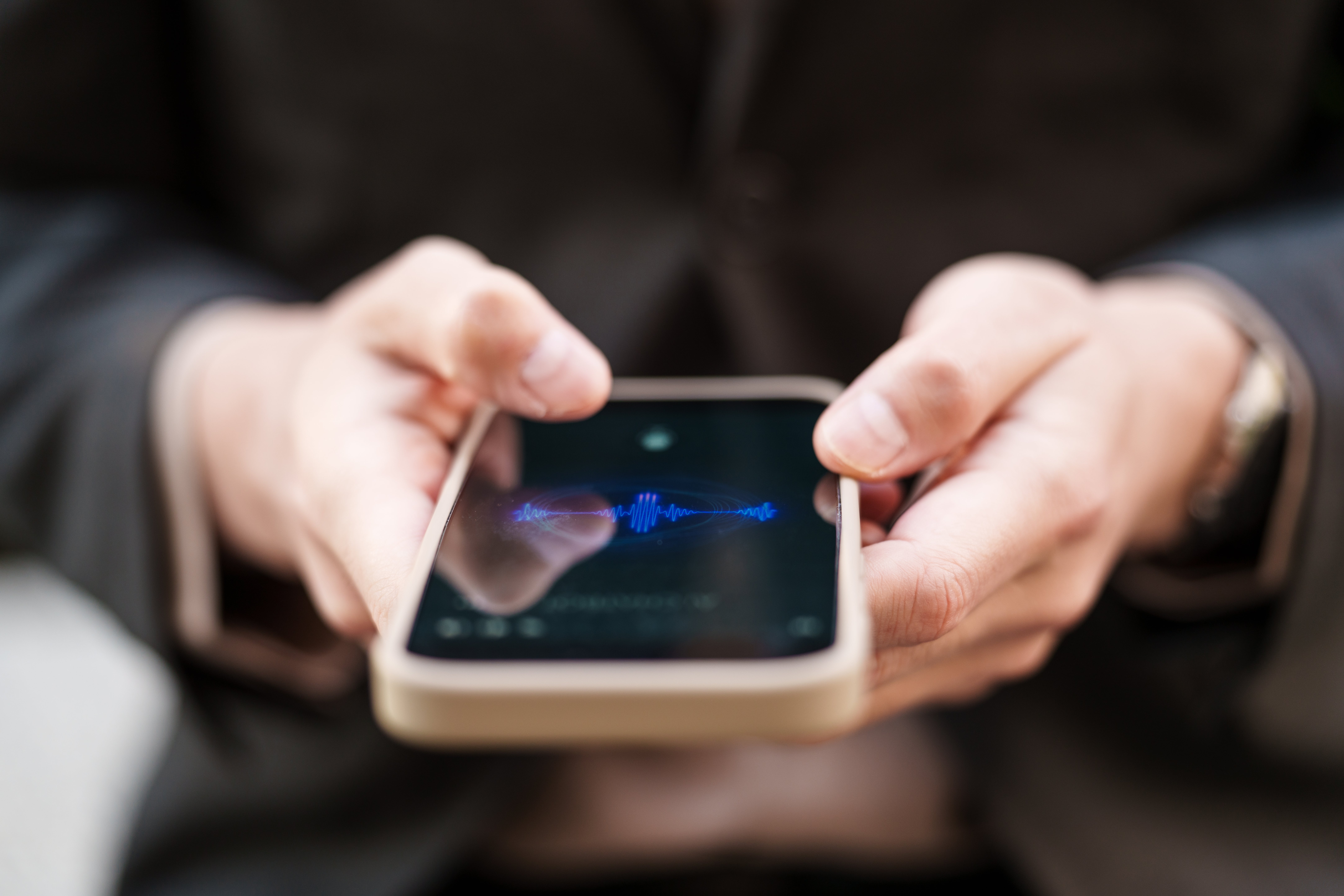 Person holding a smartphone with a soundwave signifier   connected  the screen, suggesting audio signaling  oregon  playback
