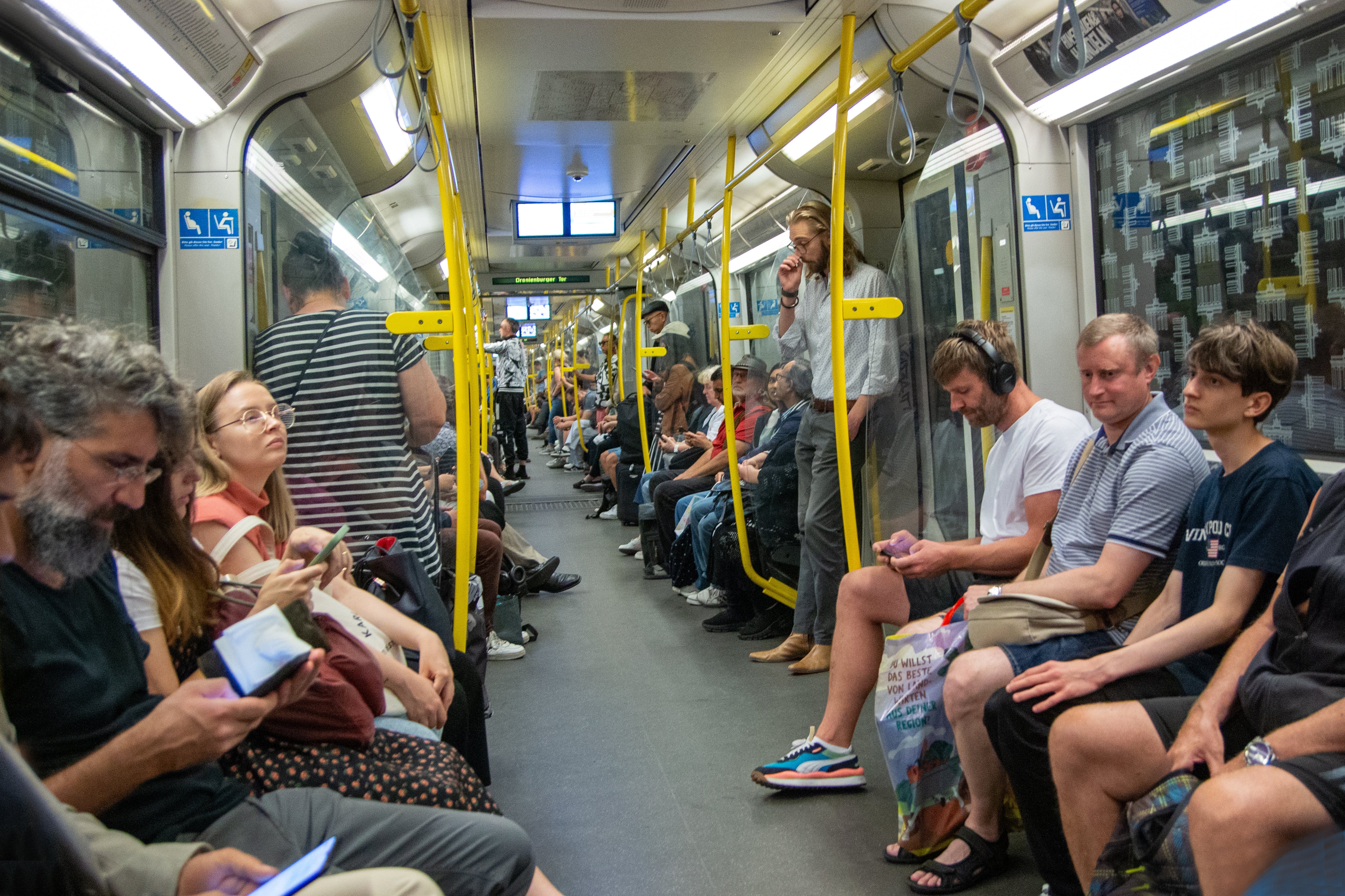 Passengers sitting and lasting  wrong  a engaged  subway train, immoderate   looking astatine  their phones, others gazing around