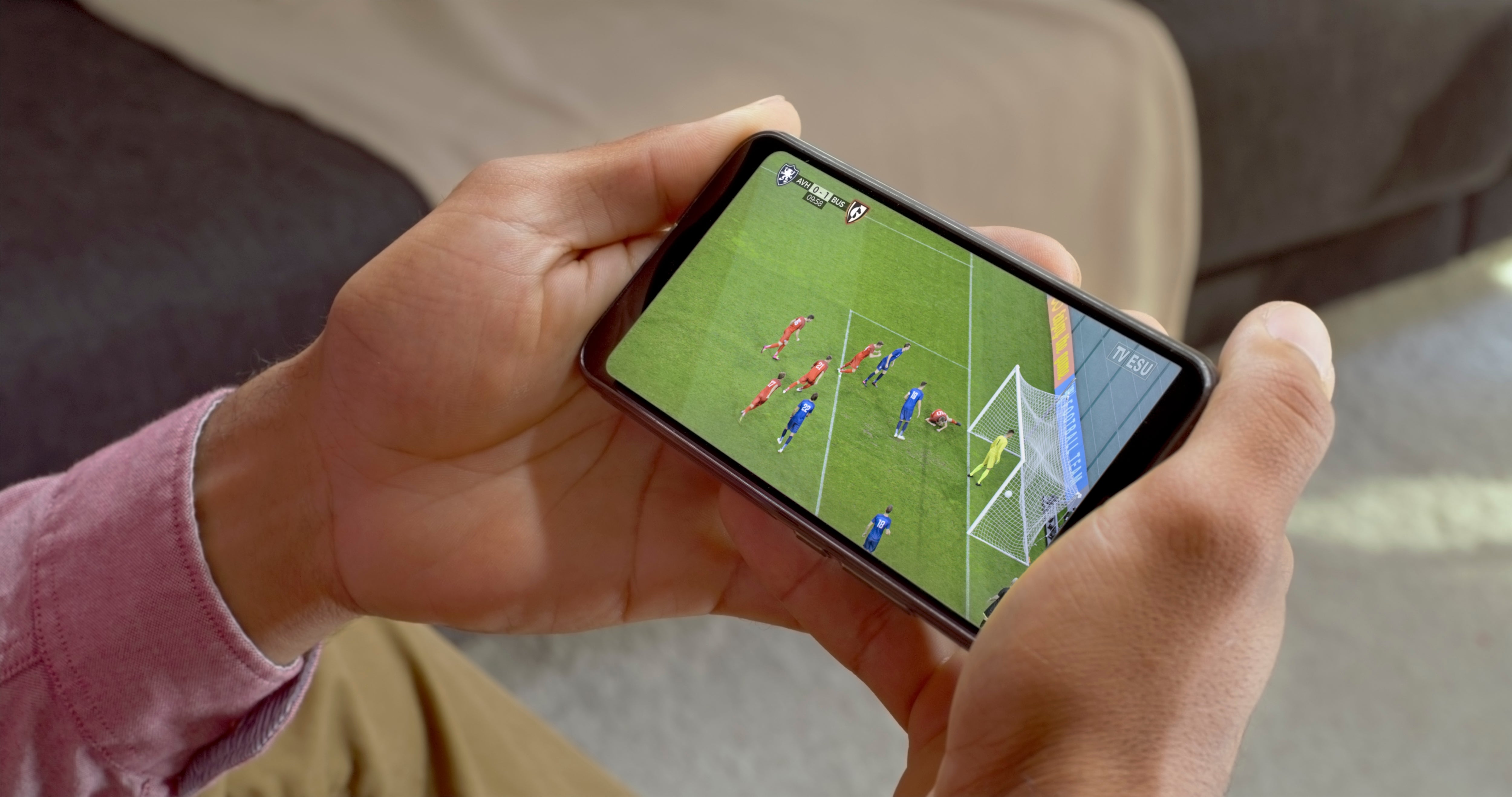 Person holding a smartphone displaying a shot    match, showing a squad  successful  bluish  attempting to people     against a squad  successful  red