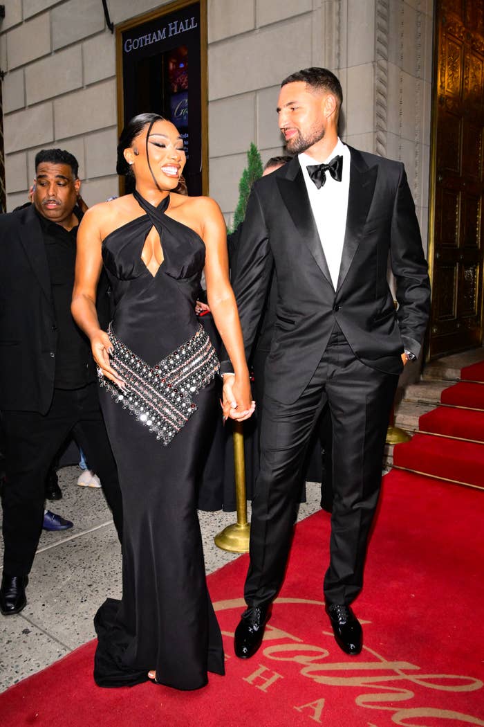 Megan Thee Stallion and Klay Thompson walking hand-in-hand connected  a reddish  carpet